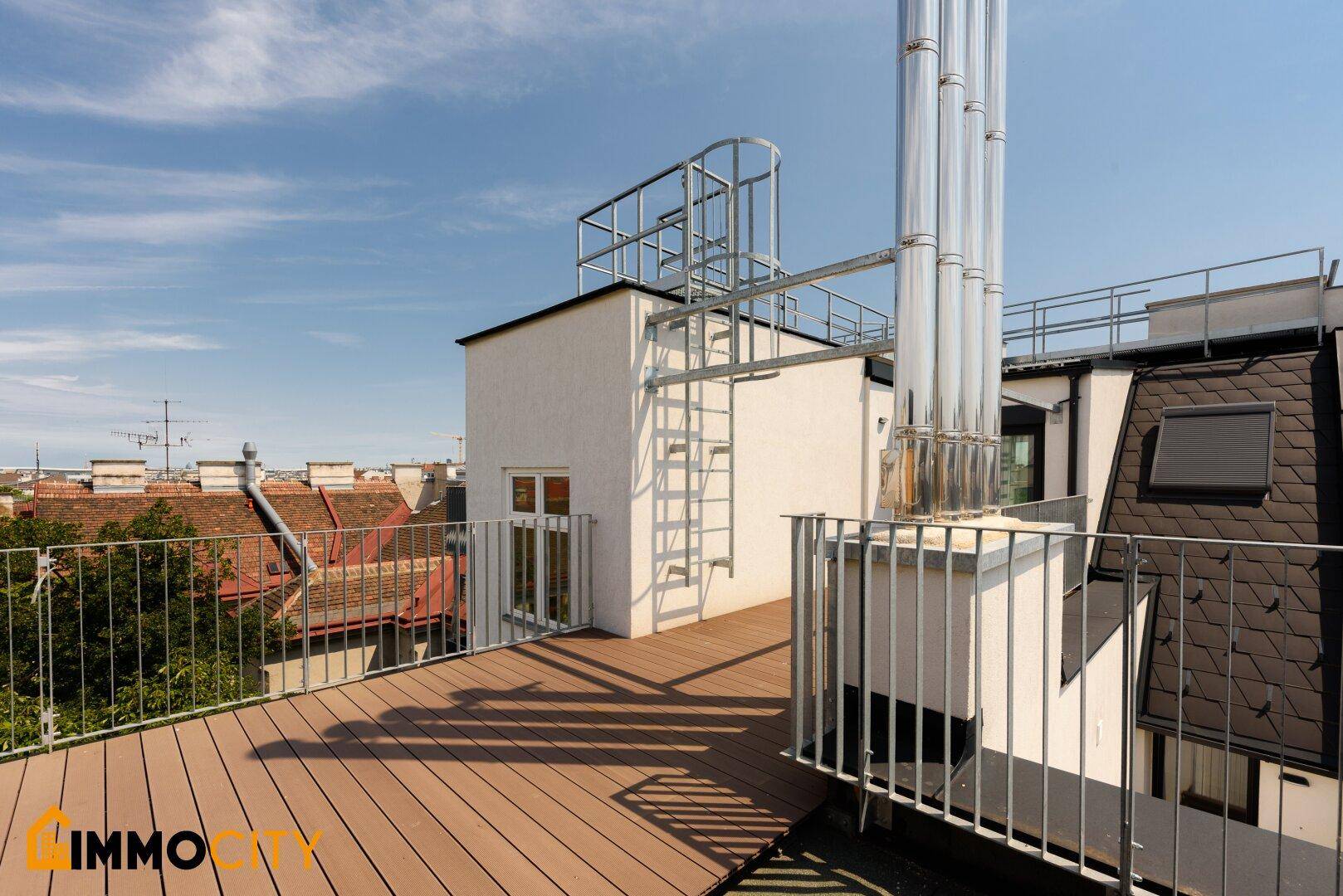 Dachterrasse mit Blick auf die Stadt, inklusive Metallstrukturen und Zugang zum Gebäude.