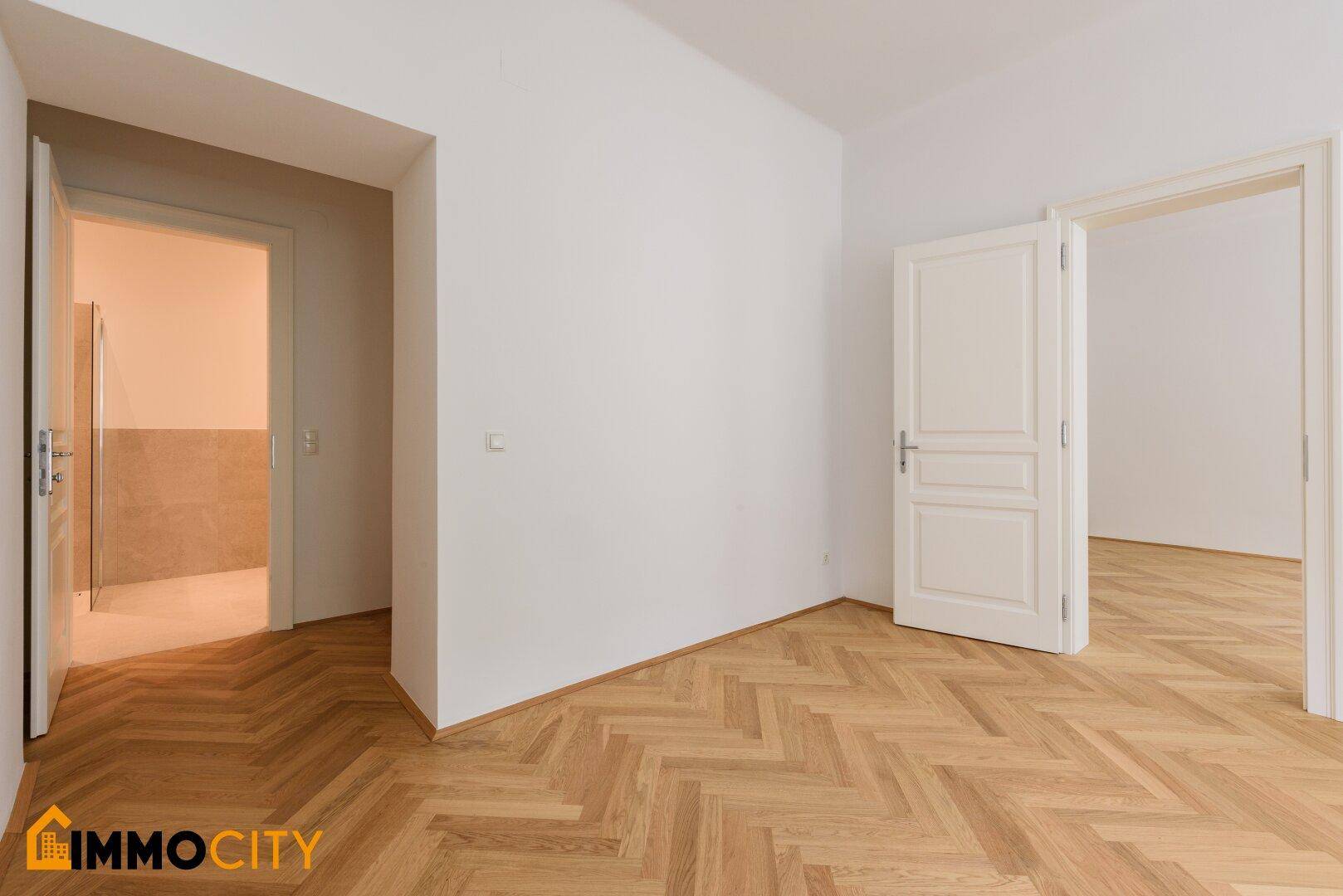 Heller Flur mit Fischgrätparkettboden und Zugang zu verschiedenen Zimmern der Wohnung.