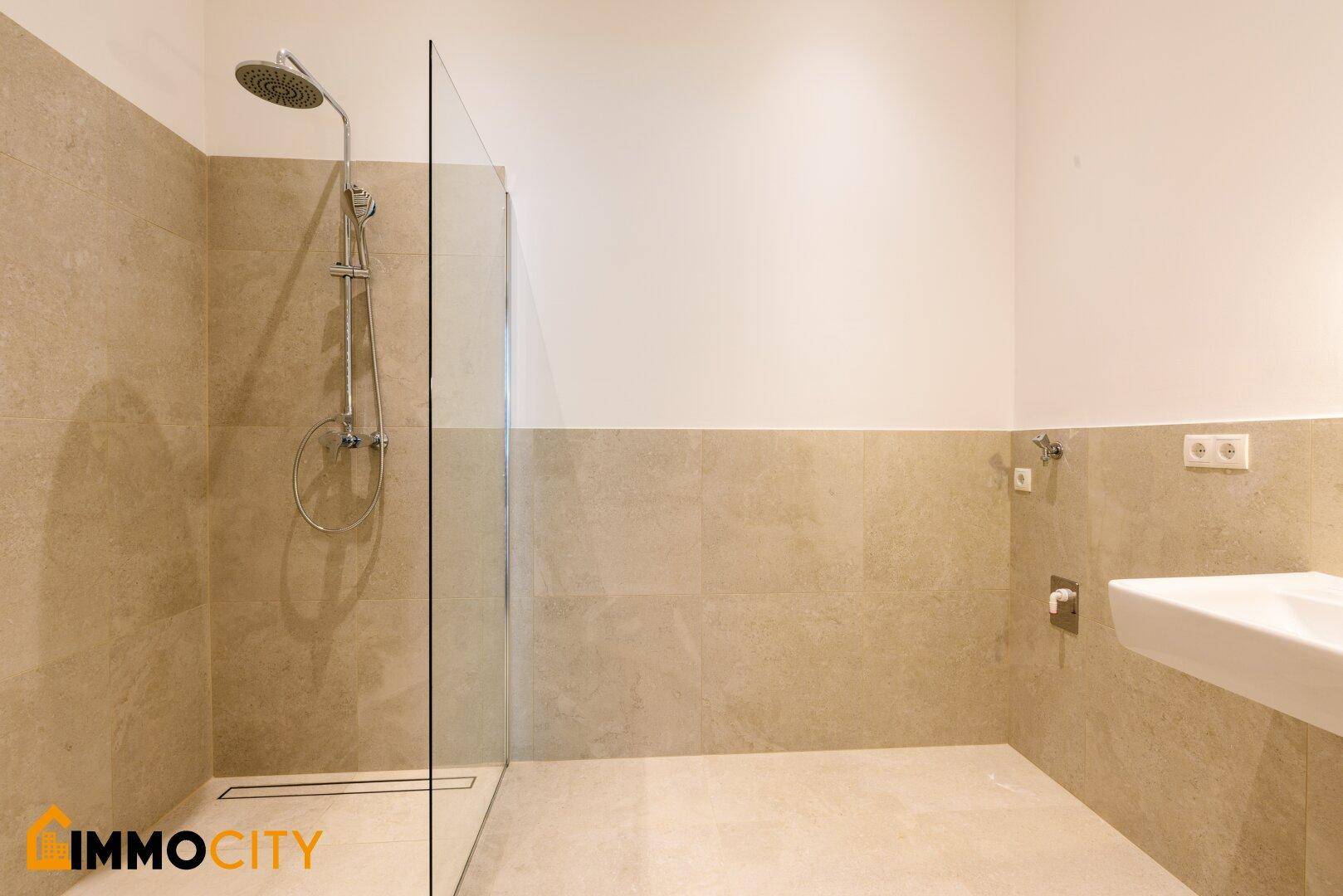 Modernes Badezimmer mit beigefarbenen Fliesen, einer begehbaren Dusche und Wandwaschbecken.