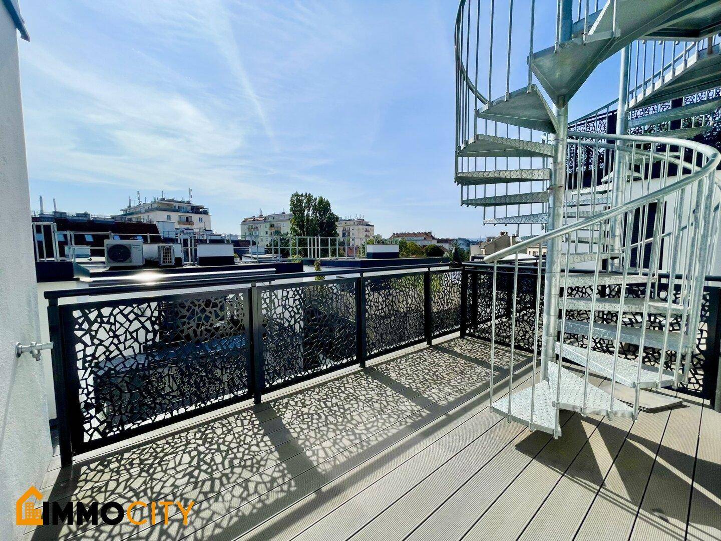 Dachterrasse mit Wendeltreppe zu einer oberen Ebene und Blick über die Stadt.