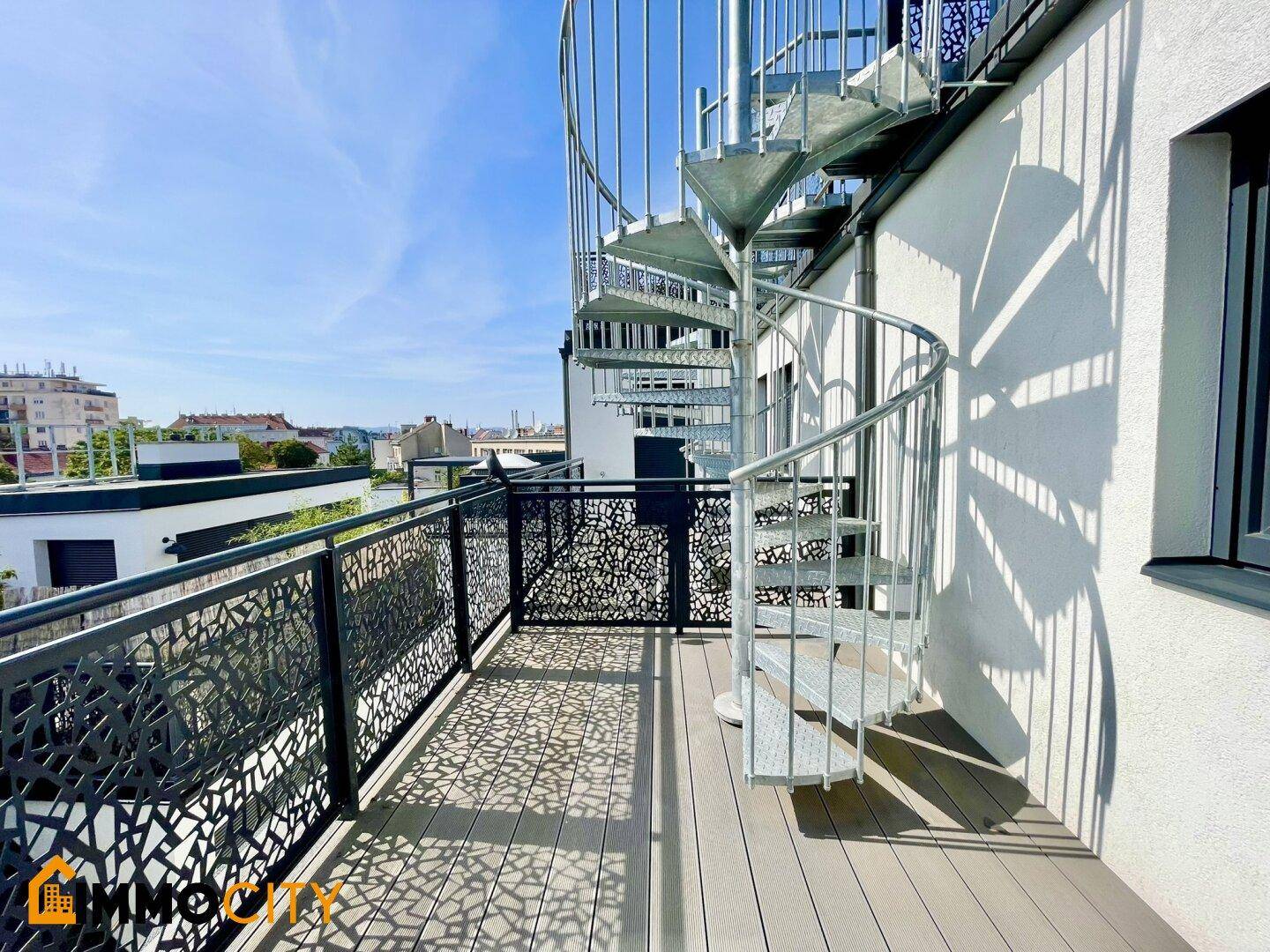 Dachterrasse mit Wendeltreppe zu einer oberen Ebene und Blick über die Stadt.