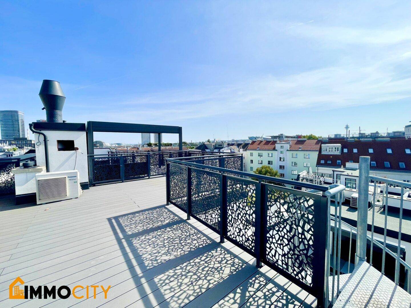 Weitläufige Dachterrasse mit Holzboden, Stadtblick und modernen Hochhäusern im Hintergrund.