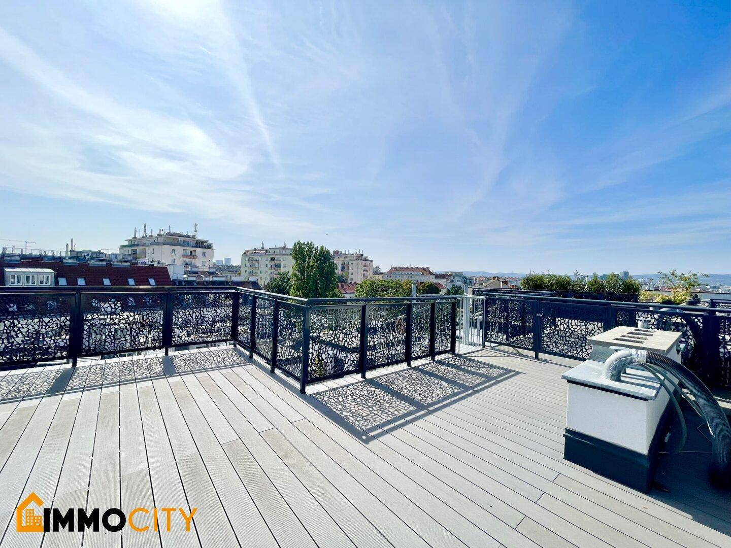 Weitläufige Dachterrasse mit Holzboden, modernem Geländer und Panoramablick über die Stadt.