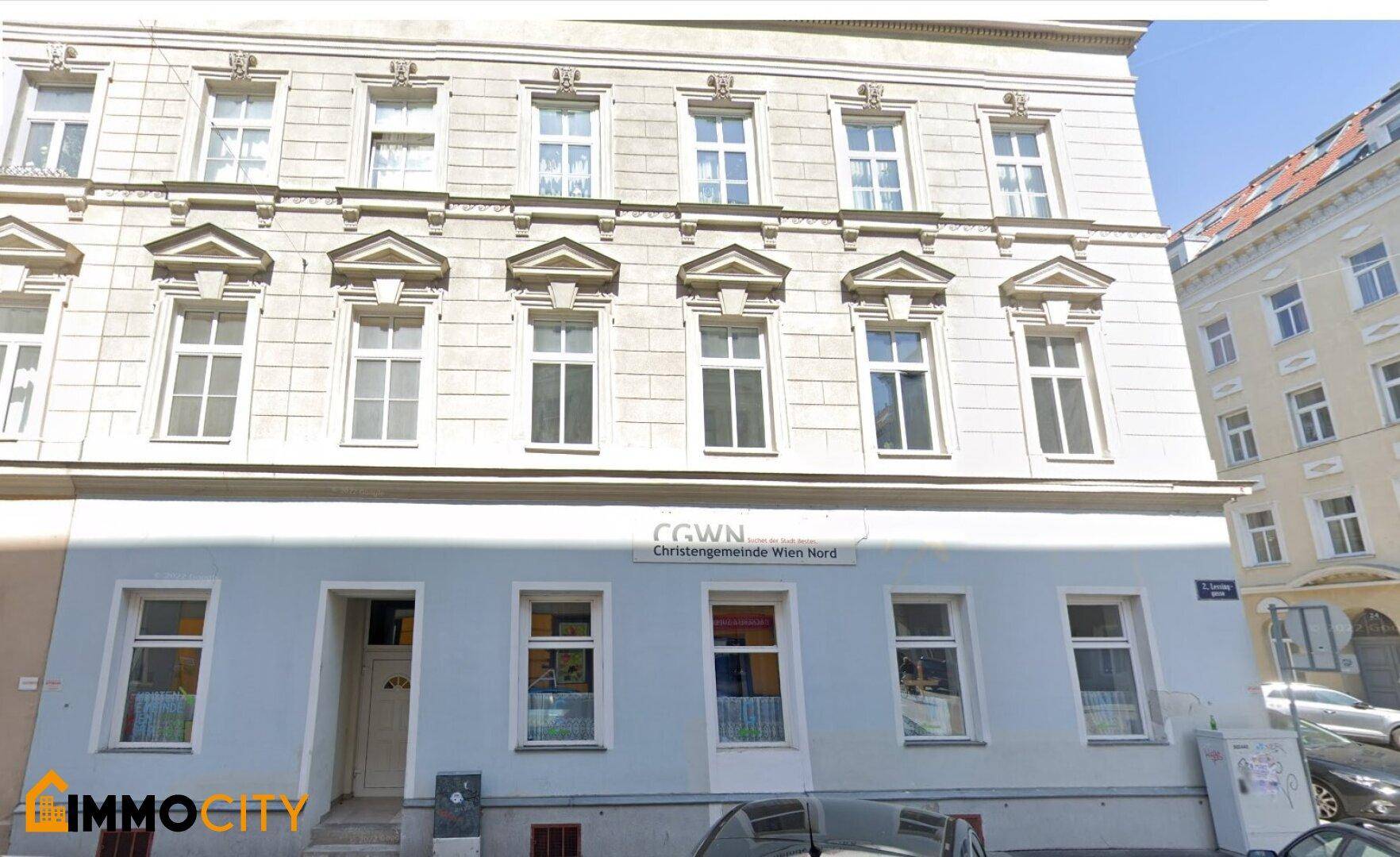 Detailansicht der Fassade eines Altbaus mit mehreren Fenstern und einem Eingangsbereich im Erdgeschoss.