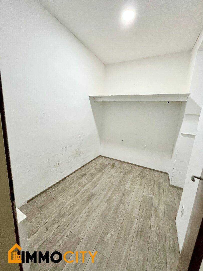 Leerer, kleiner Raum mit Laminatboden und einer einfachen Wandablage.