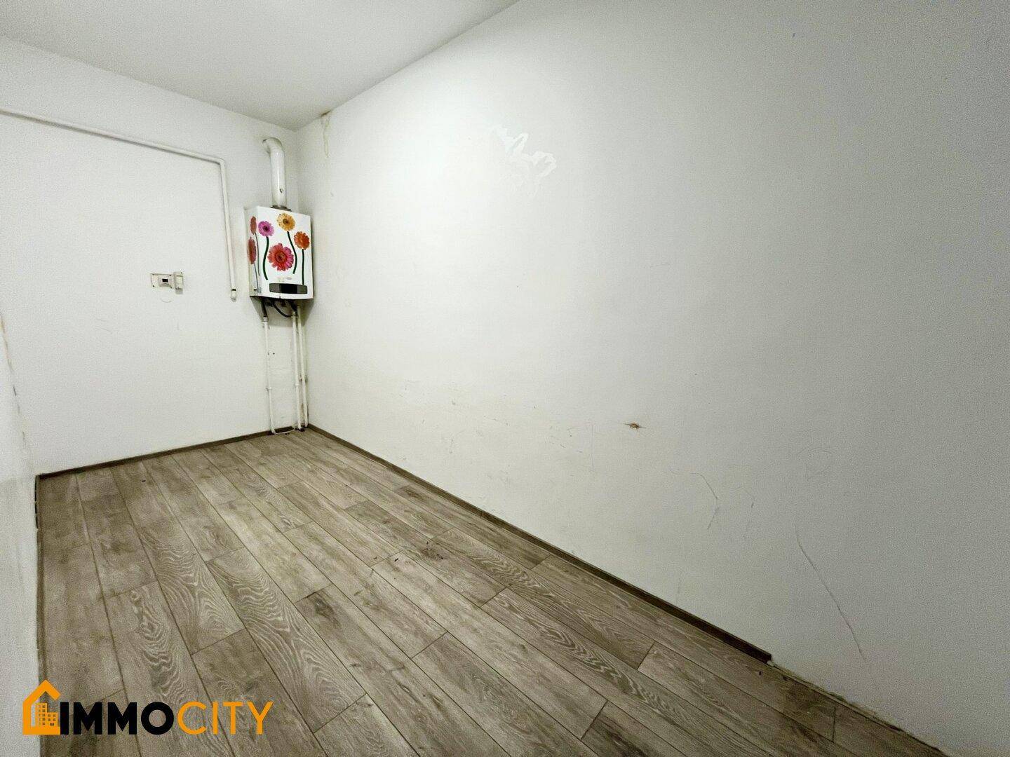 Langer, schmaler Raum mit Laminatboden und einem an der Wand montierten Heizkessel.