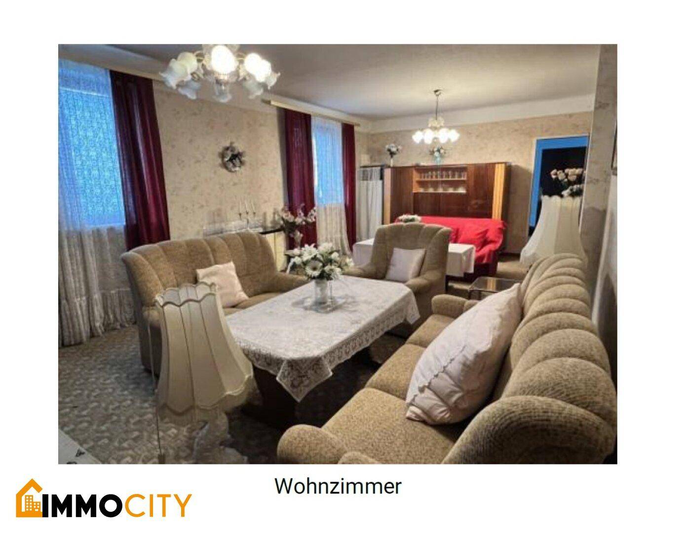 Gemütliches Wohnzimmer mit traditionellen Möbeln, Kronleuchter und gemusterten Tapeten.