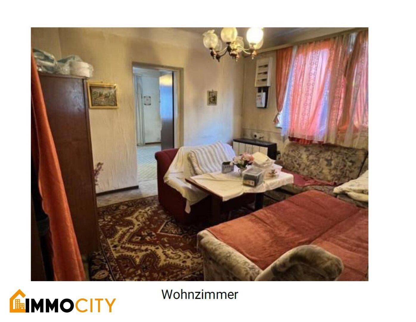 Wohnzimmer mit bequemen Sofas, Teppichboden und einem Durchgang zu einem weiteren Raum.