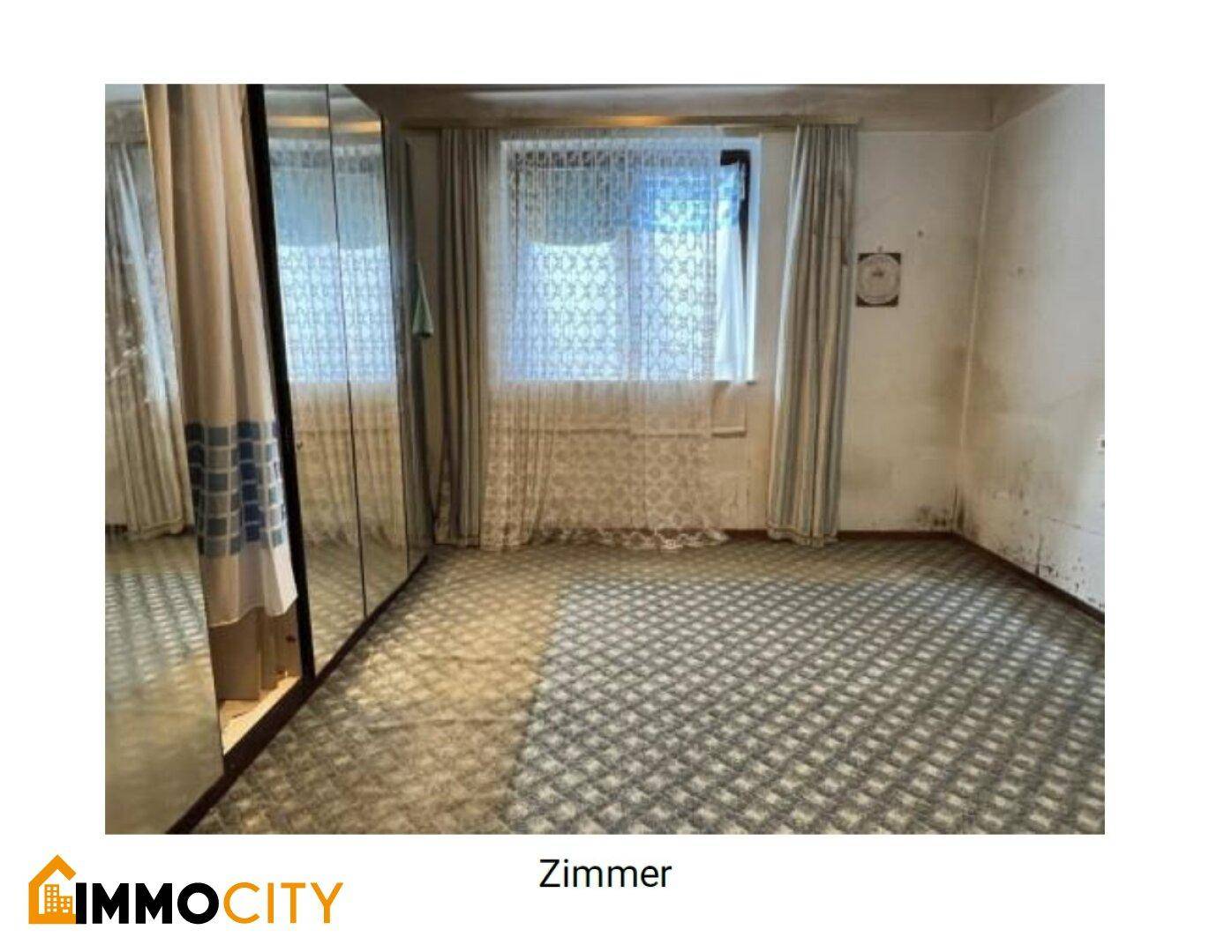 Leeres Zimmer mit gemustertem Teppichboden, Spiegelschrank und Fenster für natürliches Licht.