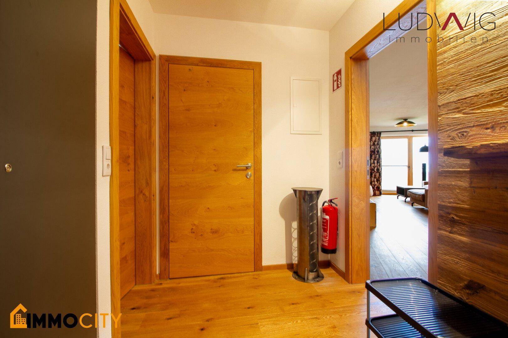 Heller Flur mit Holzboden und Holztüren, der zu den verschiedenen Räumen führt.
