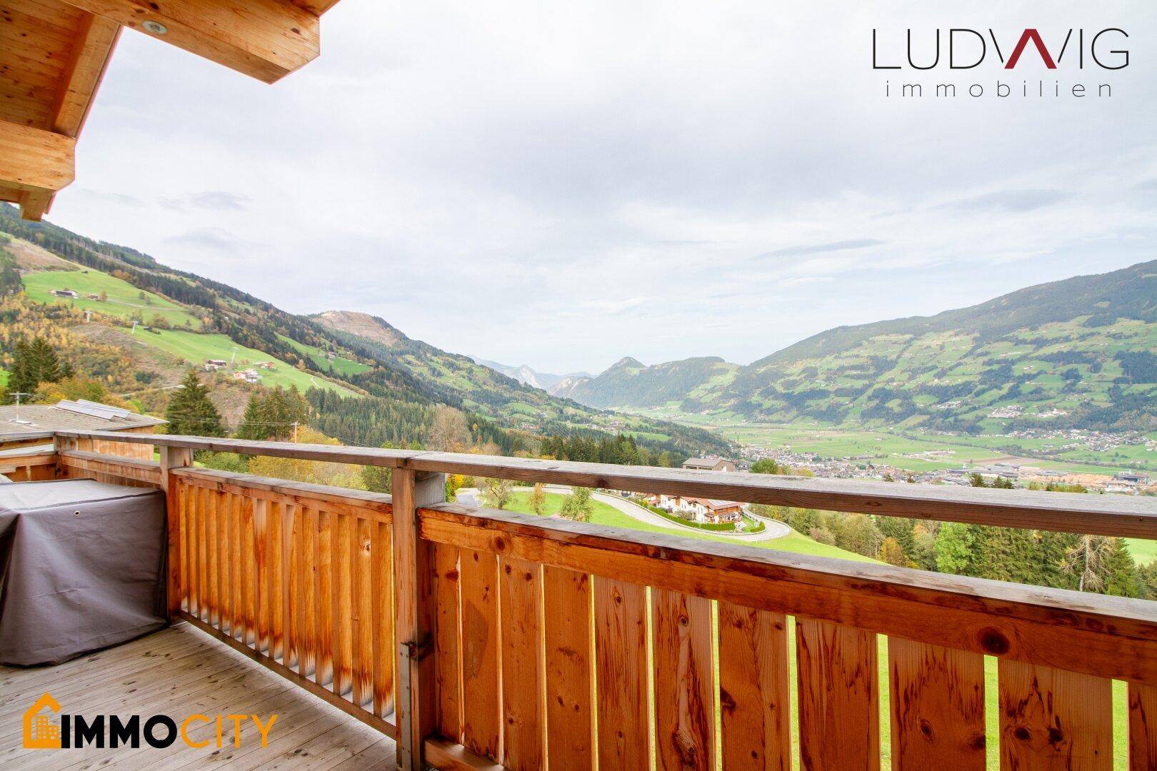 Großer Holzbalkon mit atemberaubendem Blick auf die umliegende Berglandschaft und das Tal.