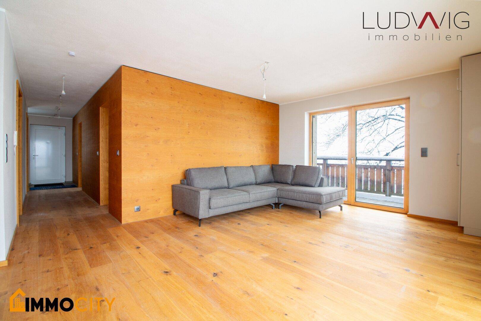 Gemütliches Wohnzimmer mit Ecksofa, Holzboden und einer stilvollen Holzwand.