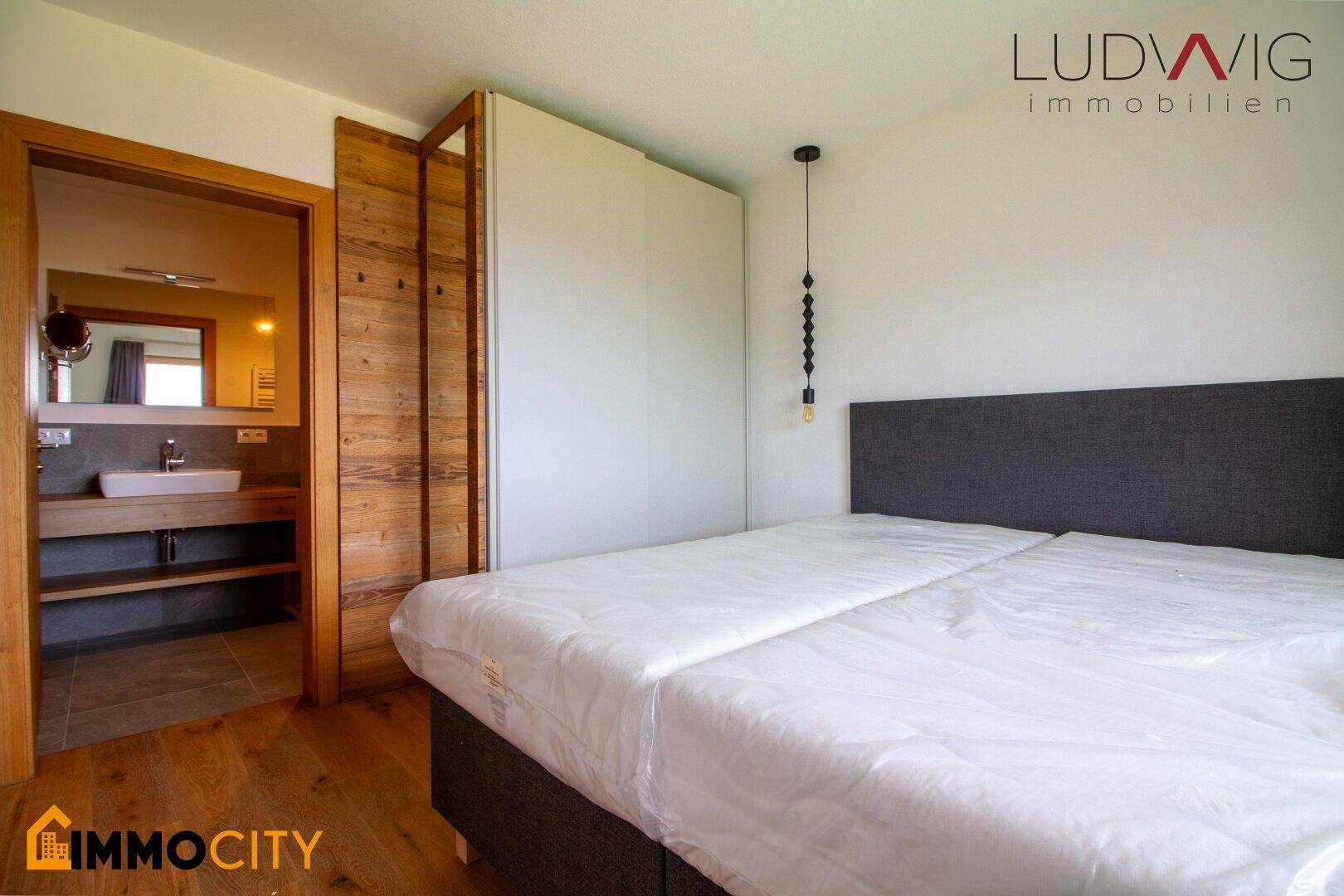 Schlafzimmer mit direktem Zugang zu einem modernen Bad und Holzboden.