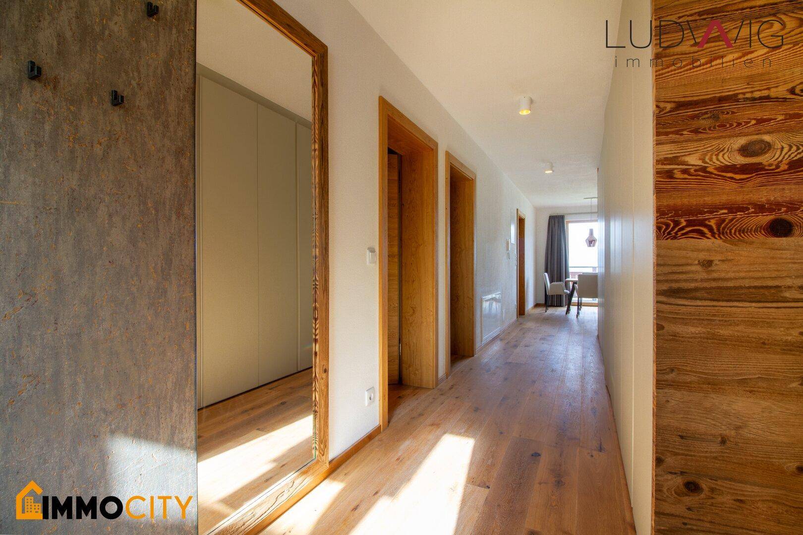 Heller Flur mit Holzboden, Holzverkleidung und einem großen Spiegel, der den Raum erweitert.