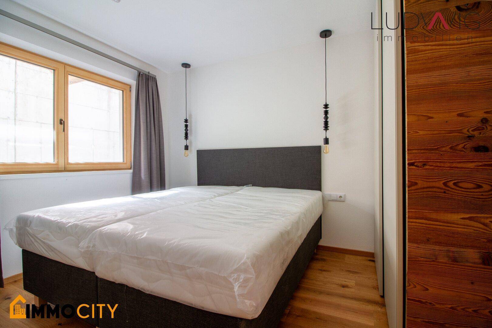 Schlafzimmer mit Holzboden, Doppelbett und Holzverkleidung, die eine warme Atmosphäre schafft.