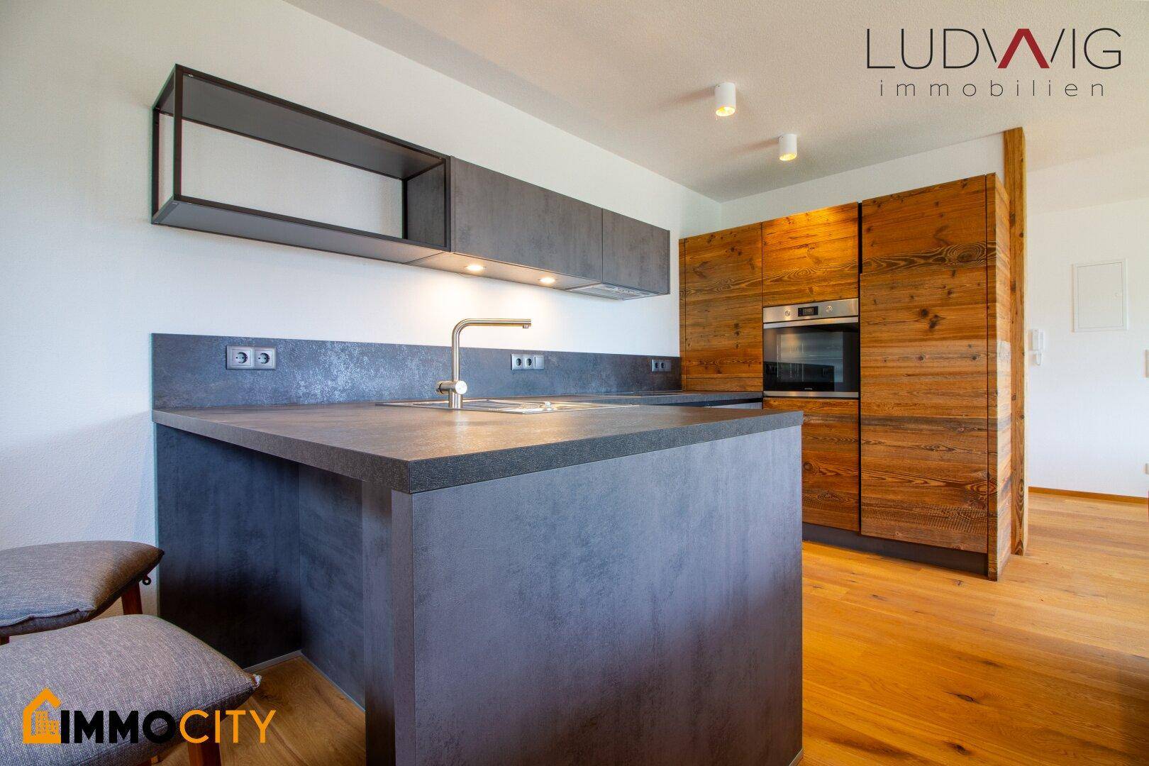 Moderne Küche mit dunklen Arbeitsplatten, Holzverkleidung und integrierten Geräten.