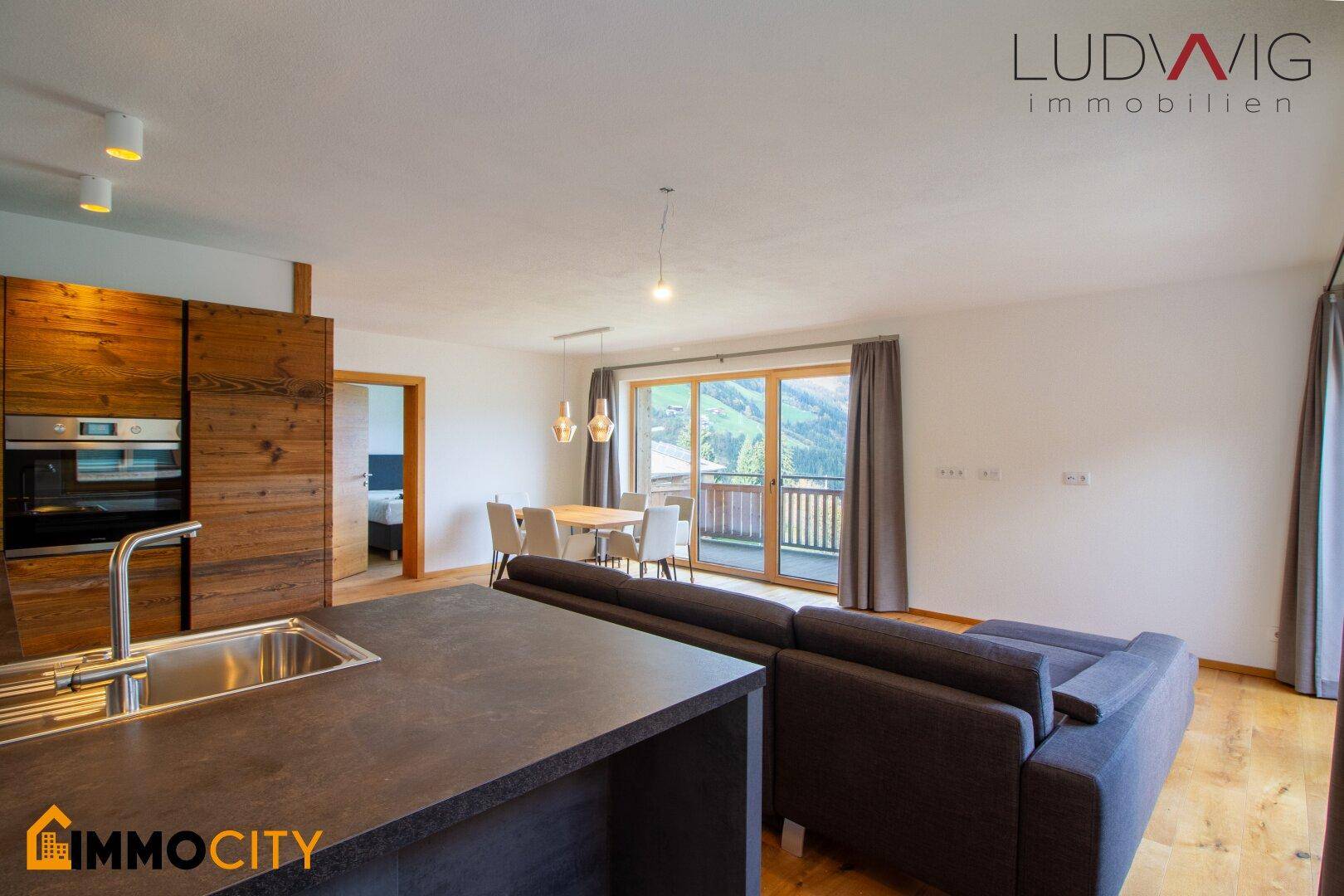 Offener Wohnbereich mit integrierter Küche, Essbereich und Zugang zum Balkon mit Bergblick.