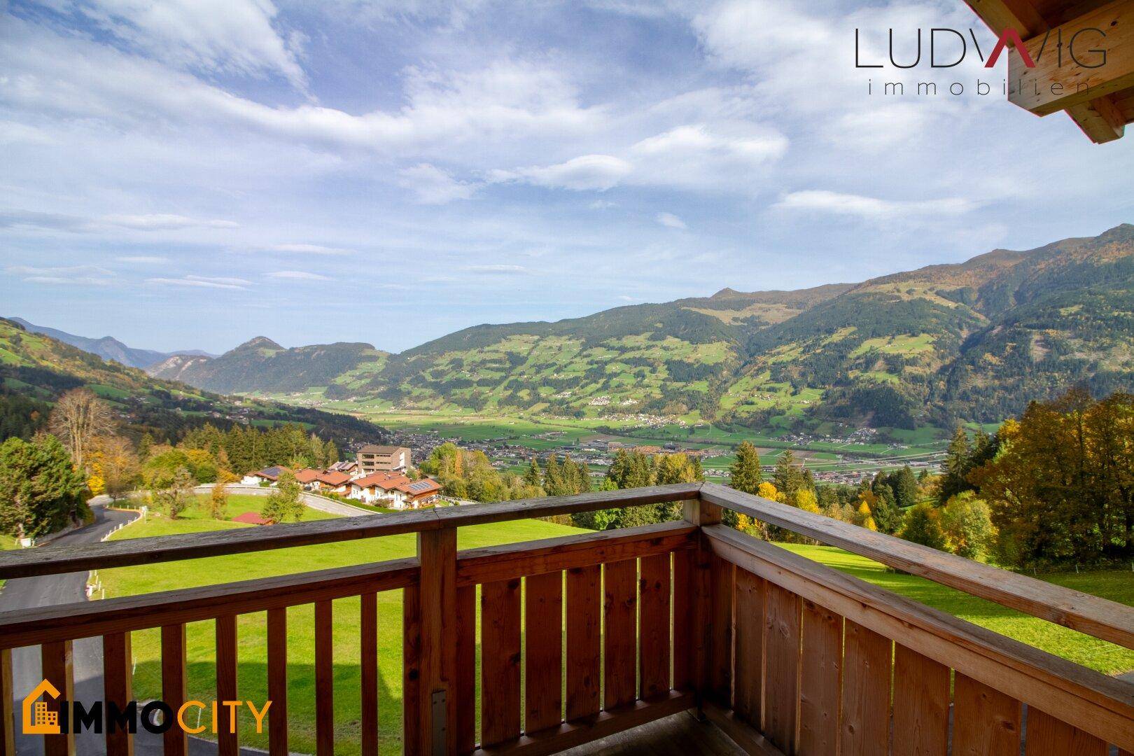 Geräumiger Holzbalkon mit atemberaubendem Blick auf die umliegende Berglandschaft und das Tal.