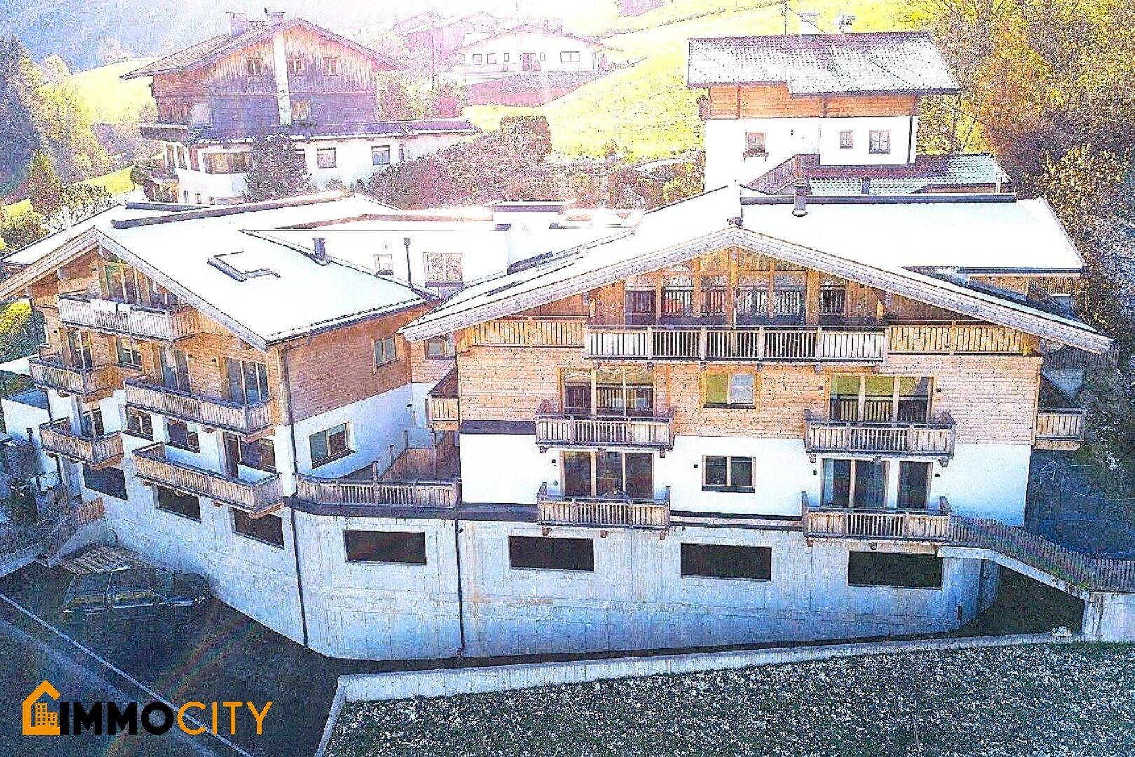 Attraktives Mehrfamilienhaus im alpinen Stil mit mehreren Balkonen und Holzfassade.