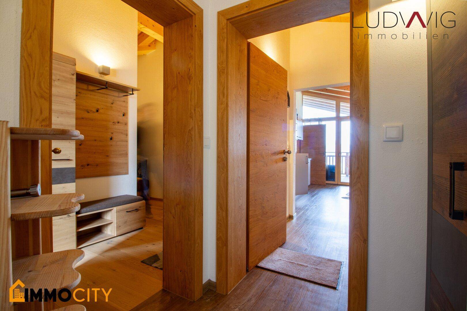 Heller Eingangsbereich mit Holztüren und Garderobe, der zu den Wohnräumen führt.