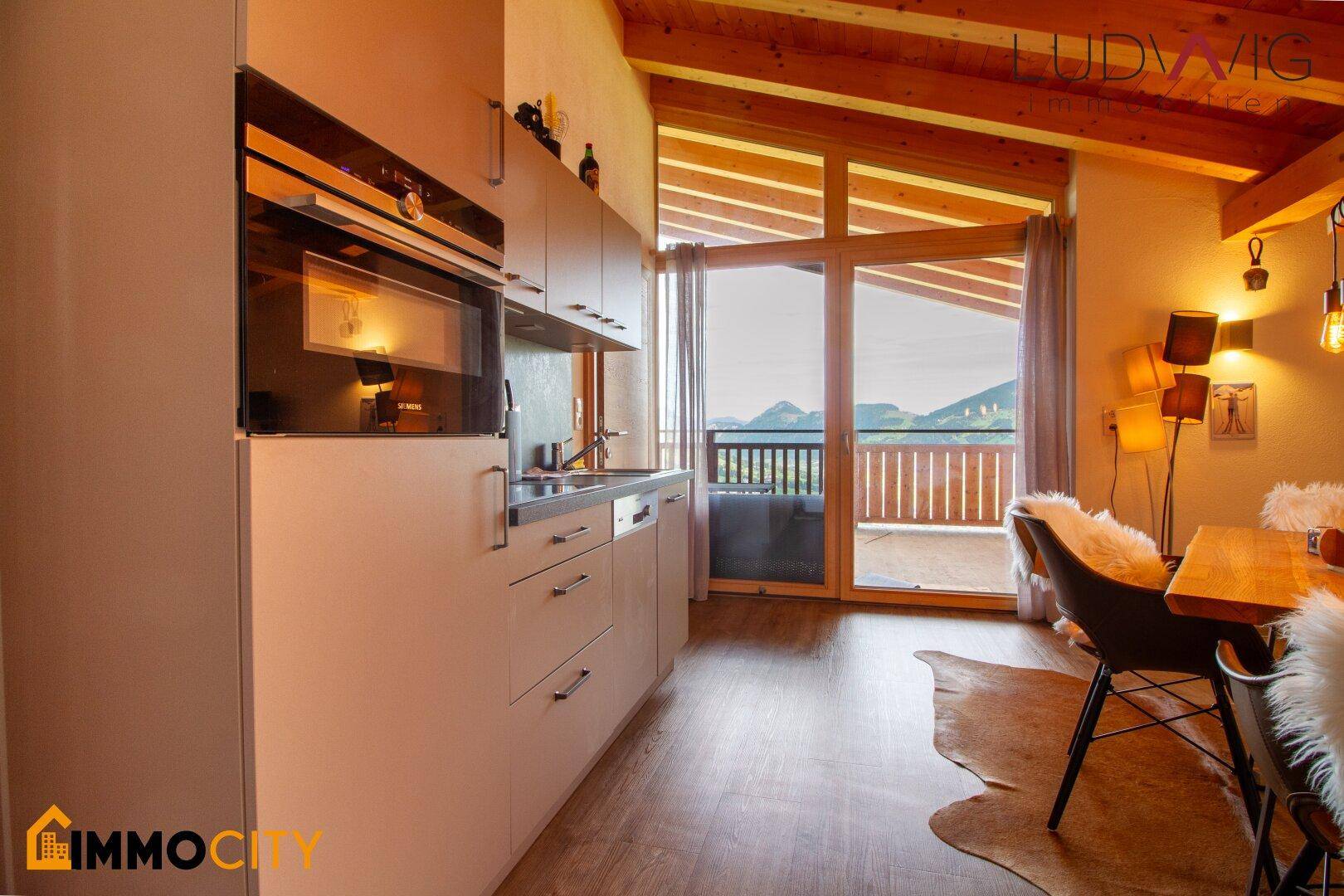 Moderne Küchenzeile mit Einbaugeräten und Zugang zu einem Balkon mit Bergblick.