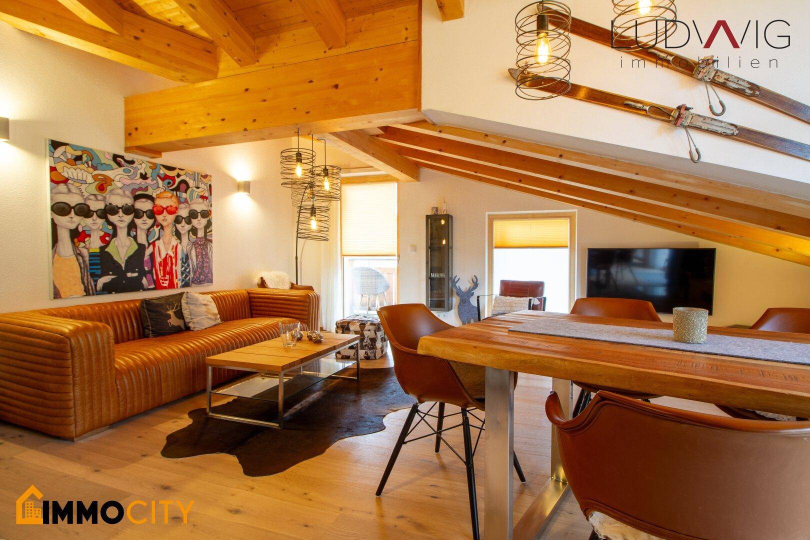 Geräumiger Wohn-Essbereich mit Holzbalken, bequemen Sofas und modernem Esstisch.