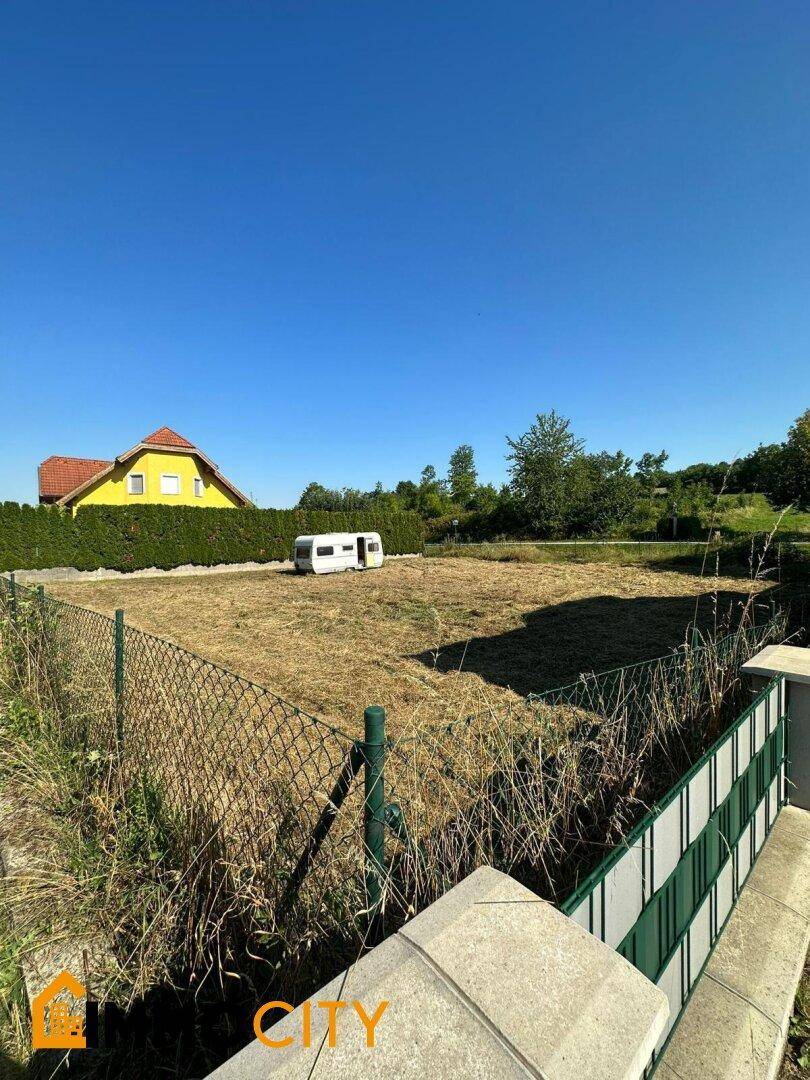 Sonniges Baugrundstück mit Blick auf die Nachbarschaft und einen Wohnwagen.