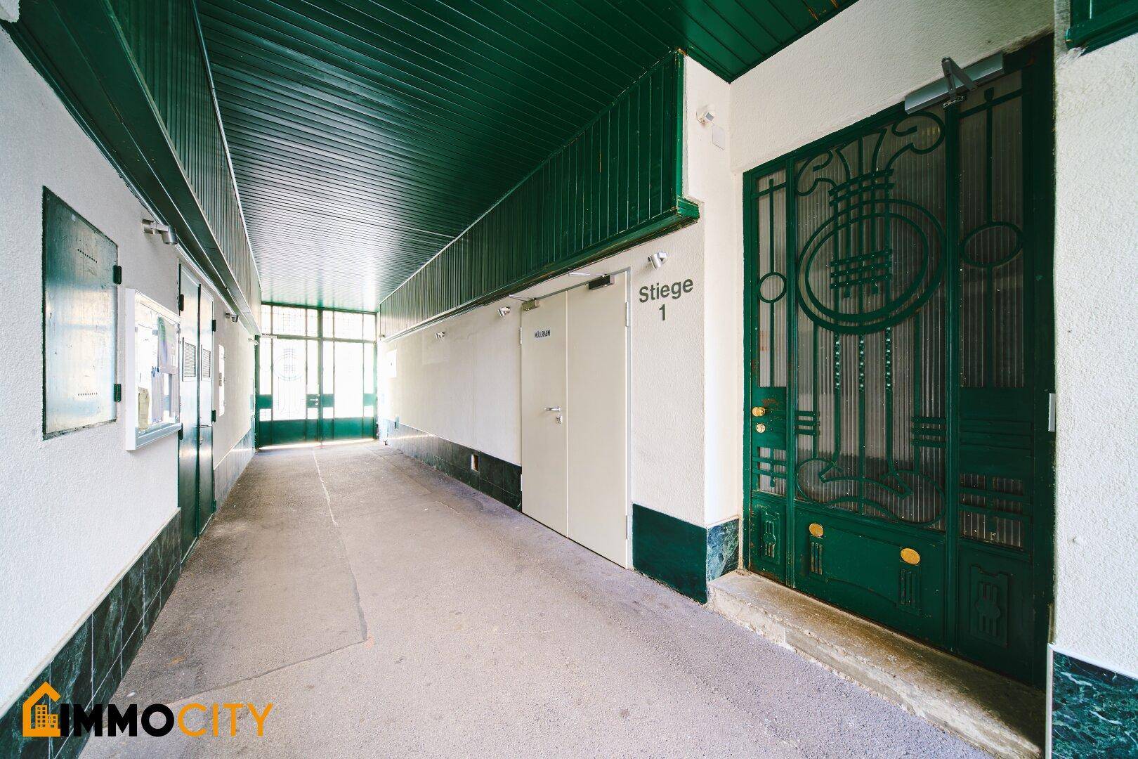 Überdachter Gang im Innenhof mit grüner Decke und dekorativem Eingangstor.