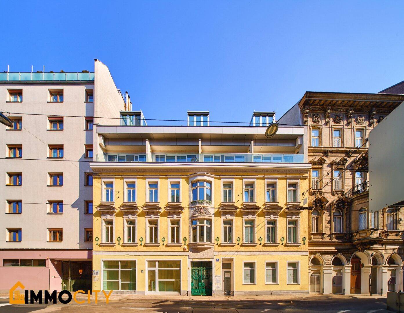 Historische Fassade eines Stadthauses mit gelbem Anstrich und vielen Fenstern.