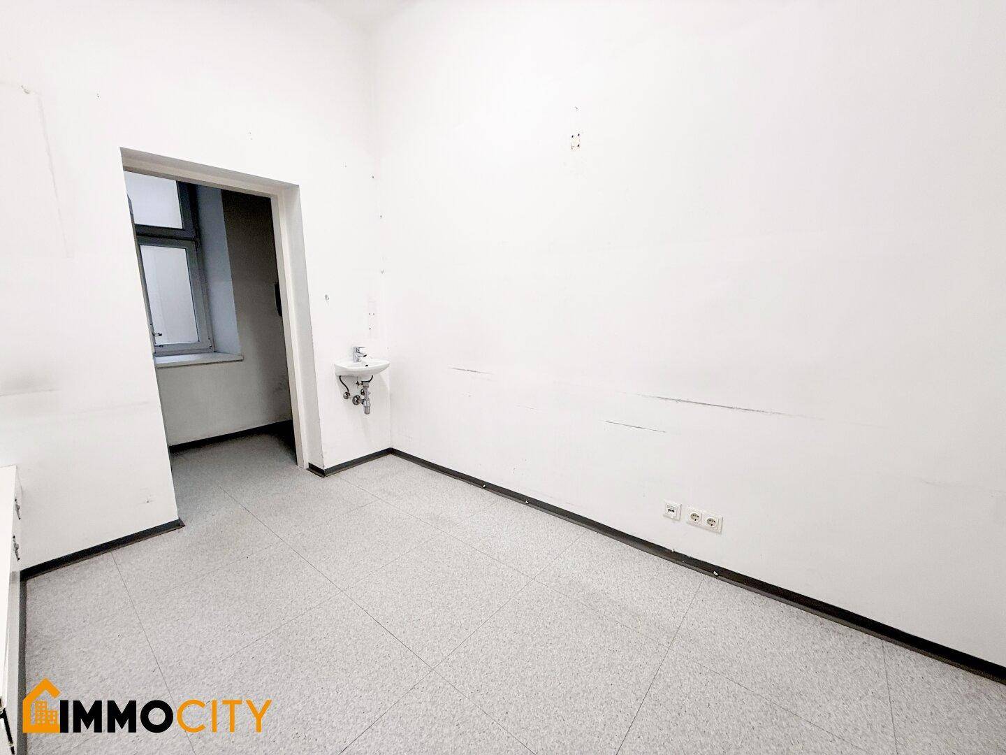Kleiner Büroraum mit Waschbecken, weißen Wänden und Fliesenboden, ideal für eine Praxis oder ein kleines Büro.