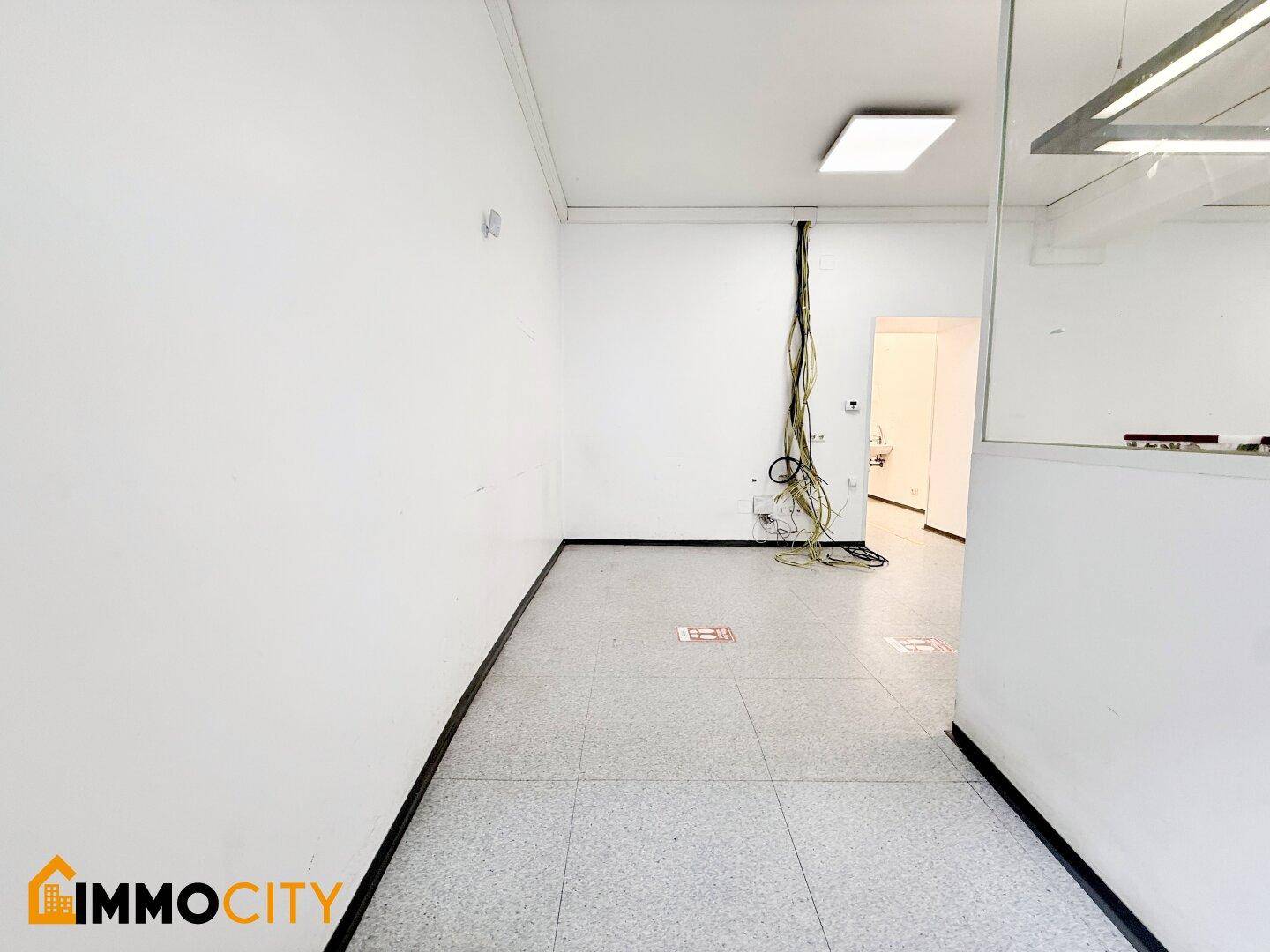 Langer Büroraum mit Fliesenboden und sichtbaren Kabeln, bietet flexible Nutzungsmöglichkeiten.