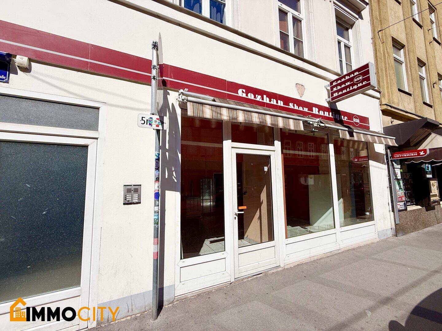 Außenansicht des Geschäftsgebäudes mit großen Schaufenstern, Markise und Eingangsbereich an der Straße.
