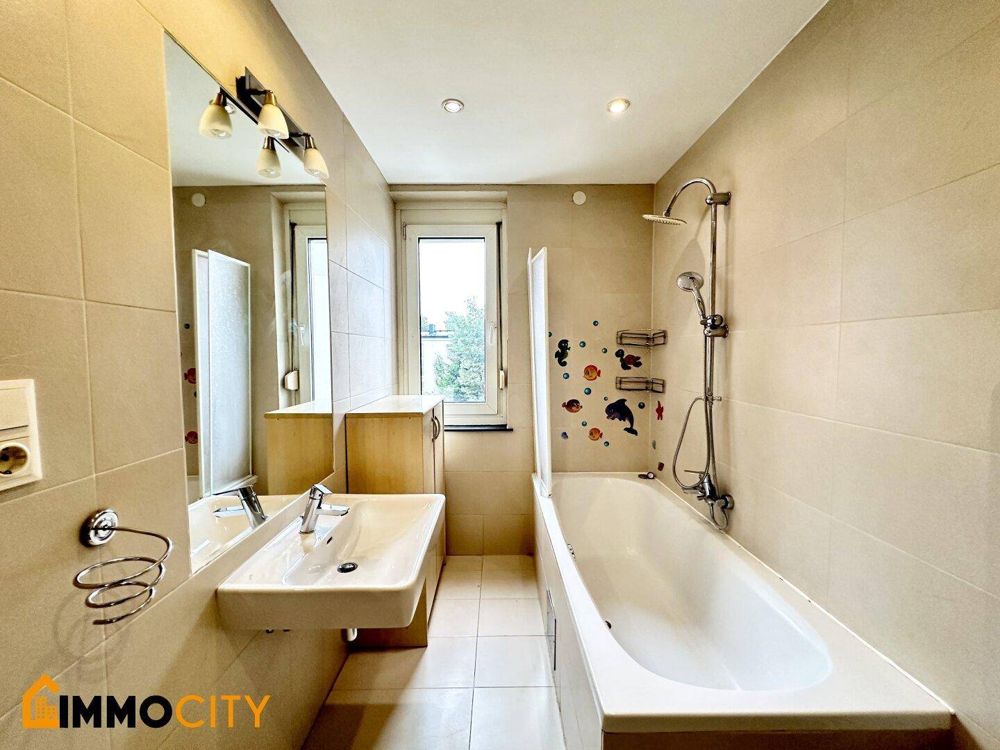 Badezimmer mit Badewanne, Dusche, Waschbecken, Fenster und einem praktischen Handtuchheizkörper.