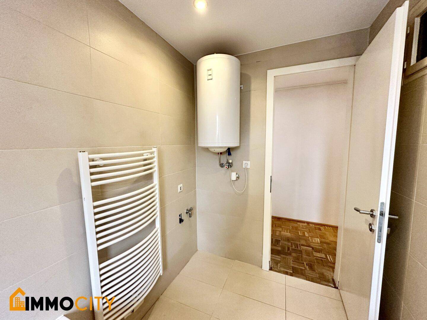 Kleiner Hauswirtschaftsraum mit Warmwasserbereiter und Handtuchheizkörper.