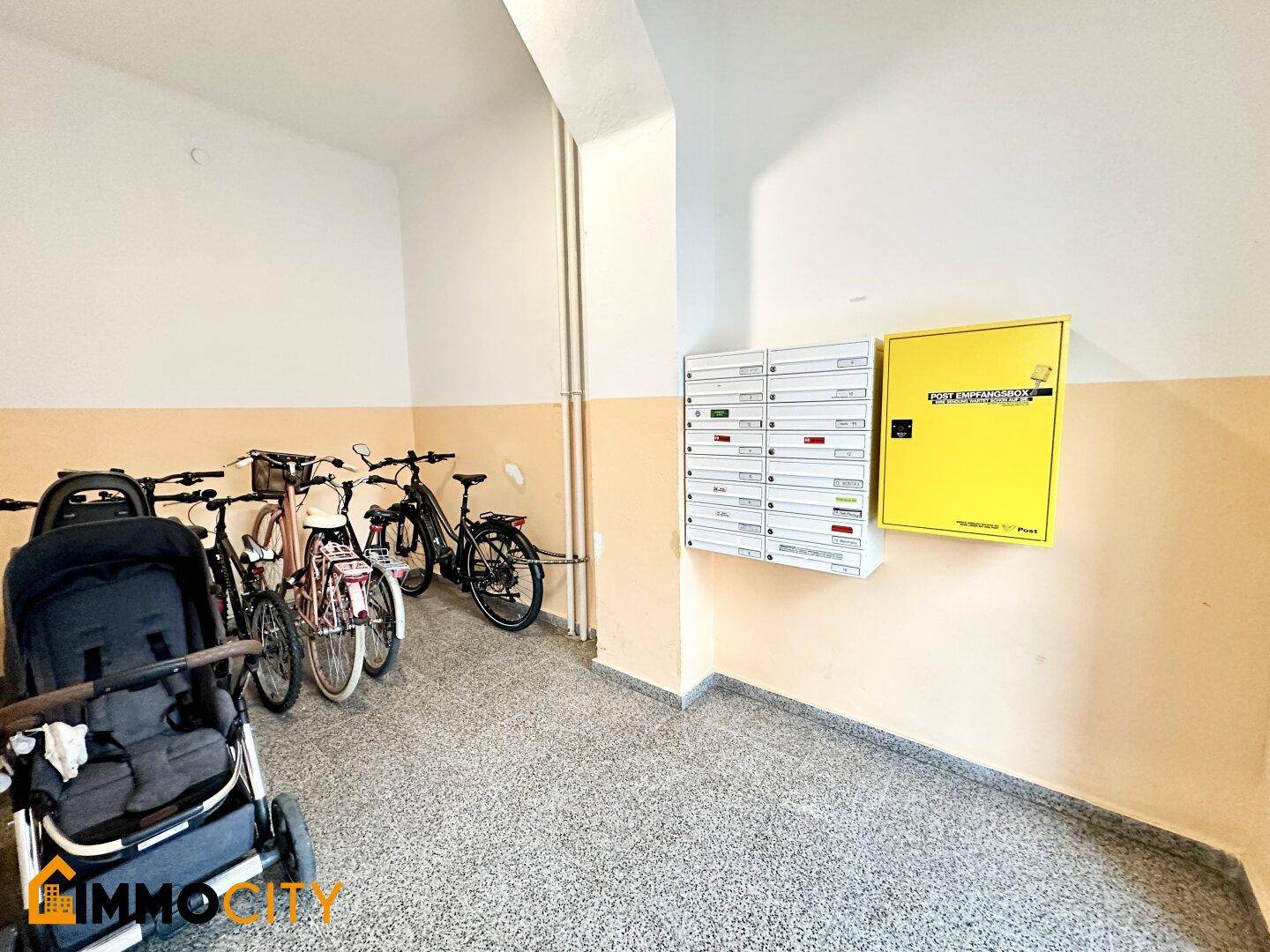 Gemeinschaftsbereich mit Briefkästen, Fahrrädern und Kinderwagen im Eingangsbereich.