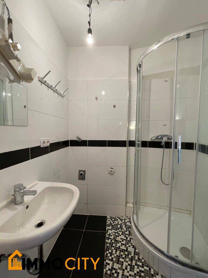 Kleines Badezimmer mit Duschkabine, Waschbecken und kontrastreichen Schwarz-Weiß-Fliesen.