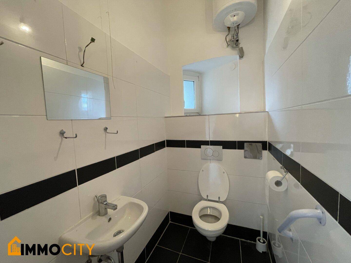 Kompaktes WC mit Toilette, Waschbecken, Spiegel und einem kleinen Fenster für Belüftung.