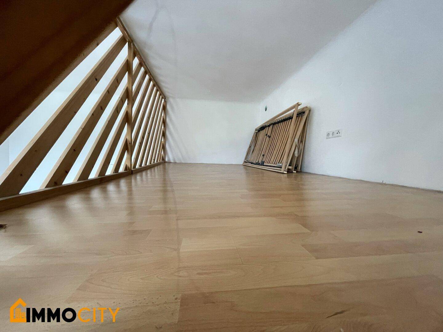Gemütliche Galerieebene mit Holzboden und schräger Decke, ideal als Schlafbereich.