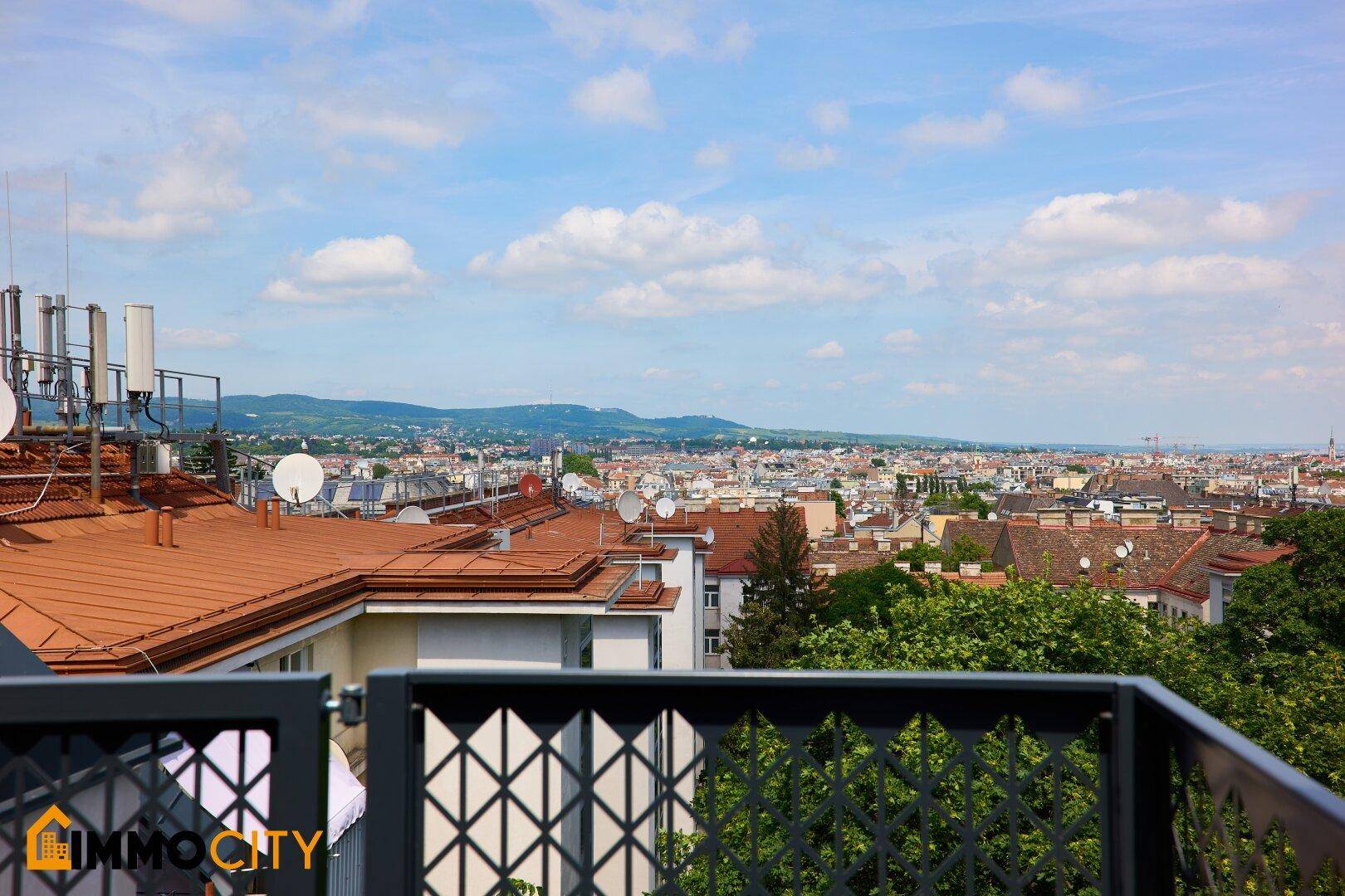 Weitläufiger Panoramablick über die Stadt mit grünen Hügeln im Hintergrund.