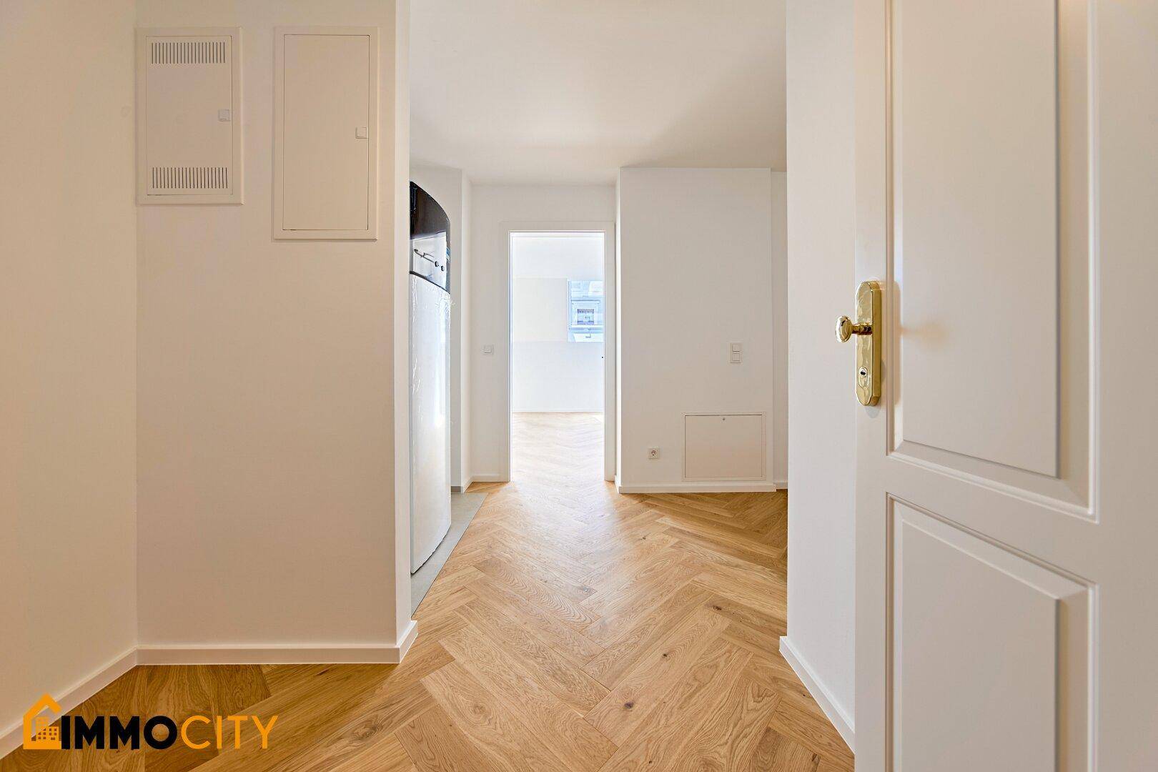 Heller Flur mit Fischgrätparkett und Zugang zu weiteren Räumen im modernen Apartment.
