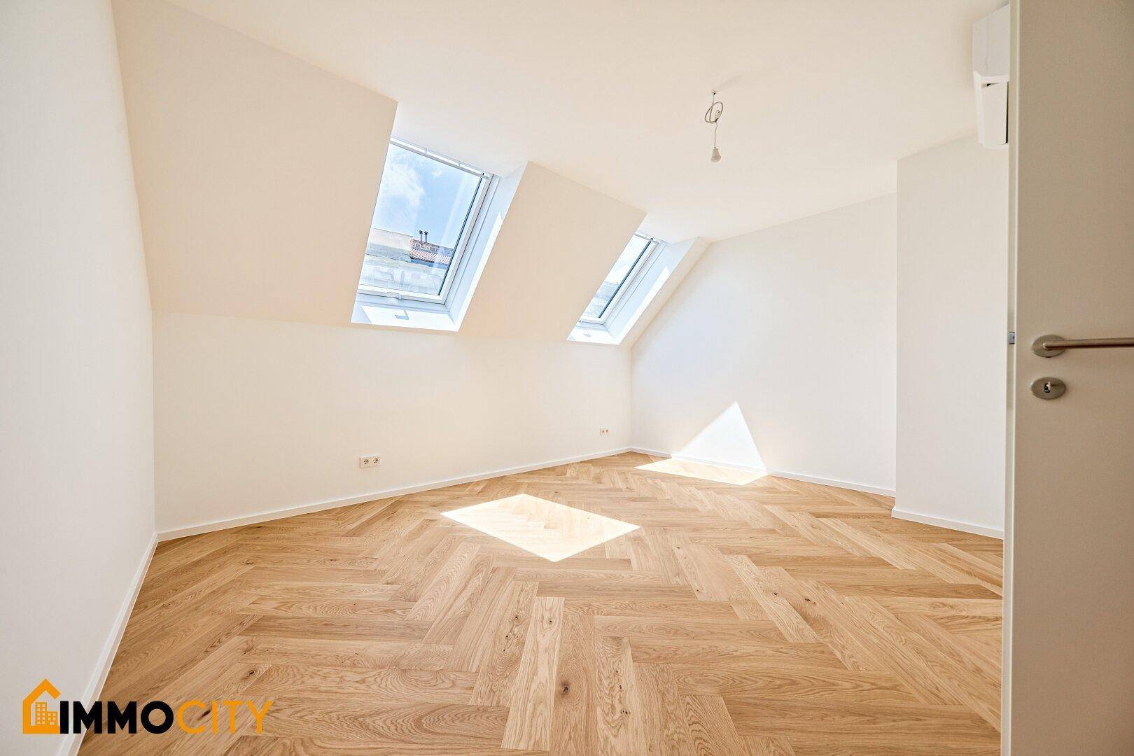 Helles Schlafzimmer mit Dachschrägen, Fischgrätparkett und zwei Dachfenstern.