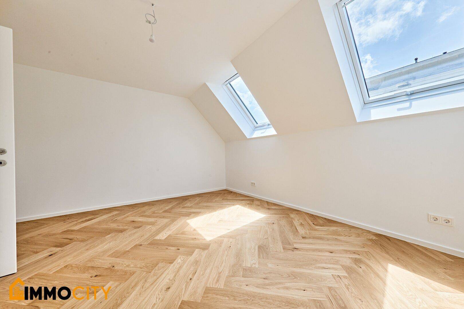 Helles Schlafzimmer mit Dachschrägen, Fischgrätparkett und Dachfenstern, die viel Licht spenden.