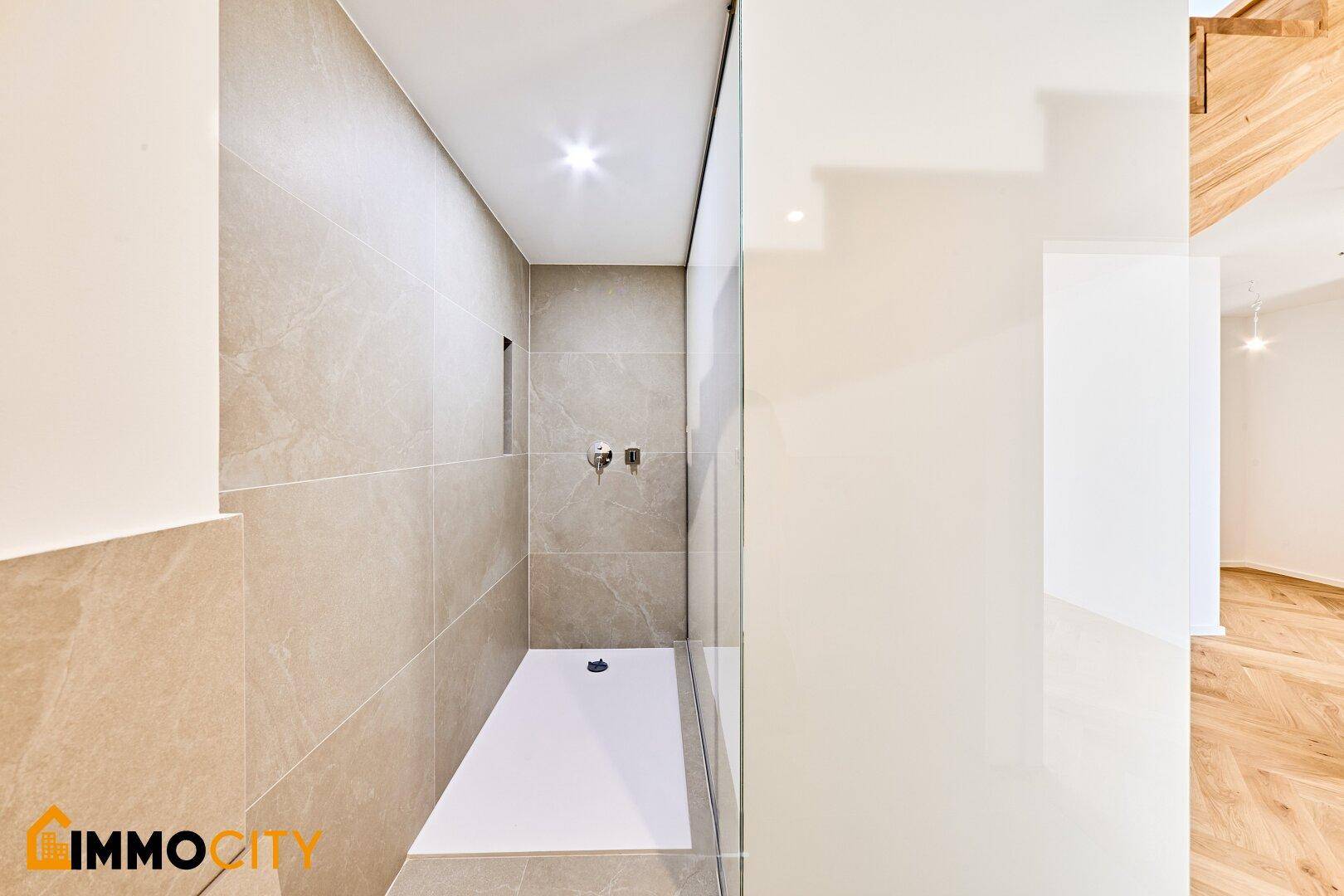 Moderne Duschkabine mit beigefarbenen Fliesen und minimalistischem Design im Badezimmer.