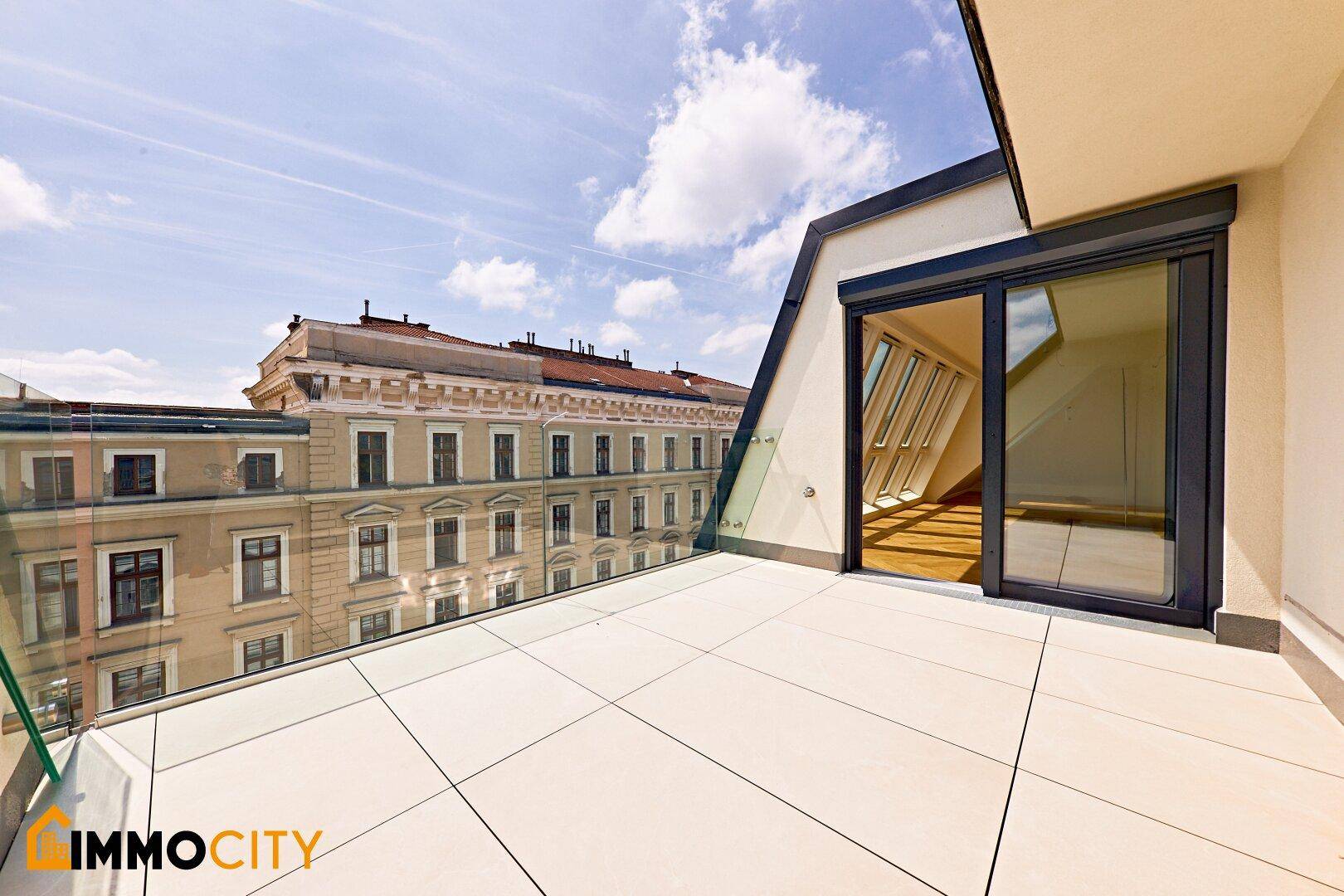 Heller Balkon mit Glasbrüstung und Blick auf die gegenüberliegenden historischen Gebäude.
