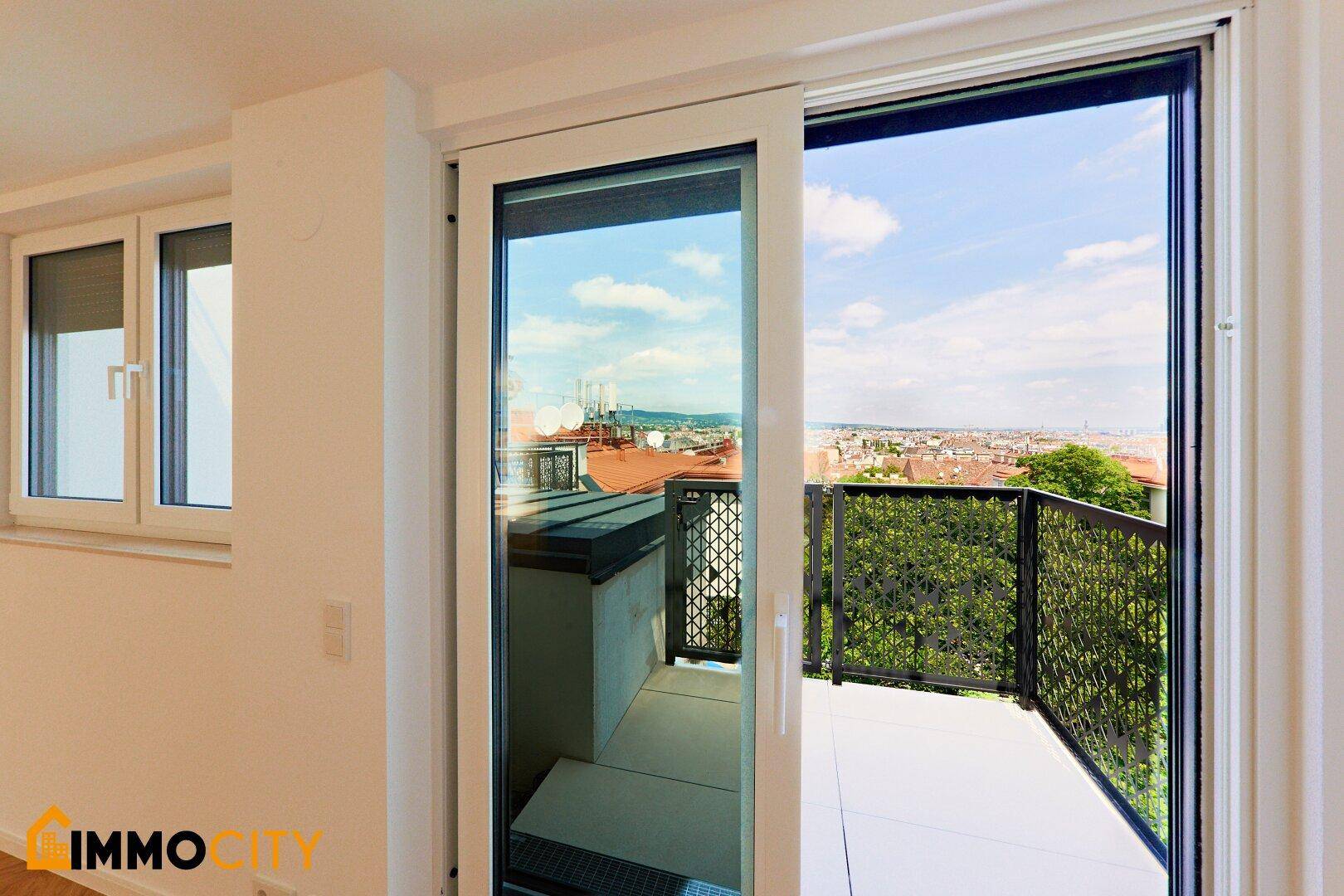 Kleiner Balkon mit Metallgeländer und weitem Blick über die Dächer der Stadt.
