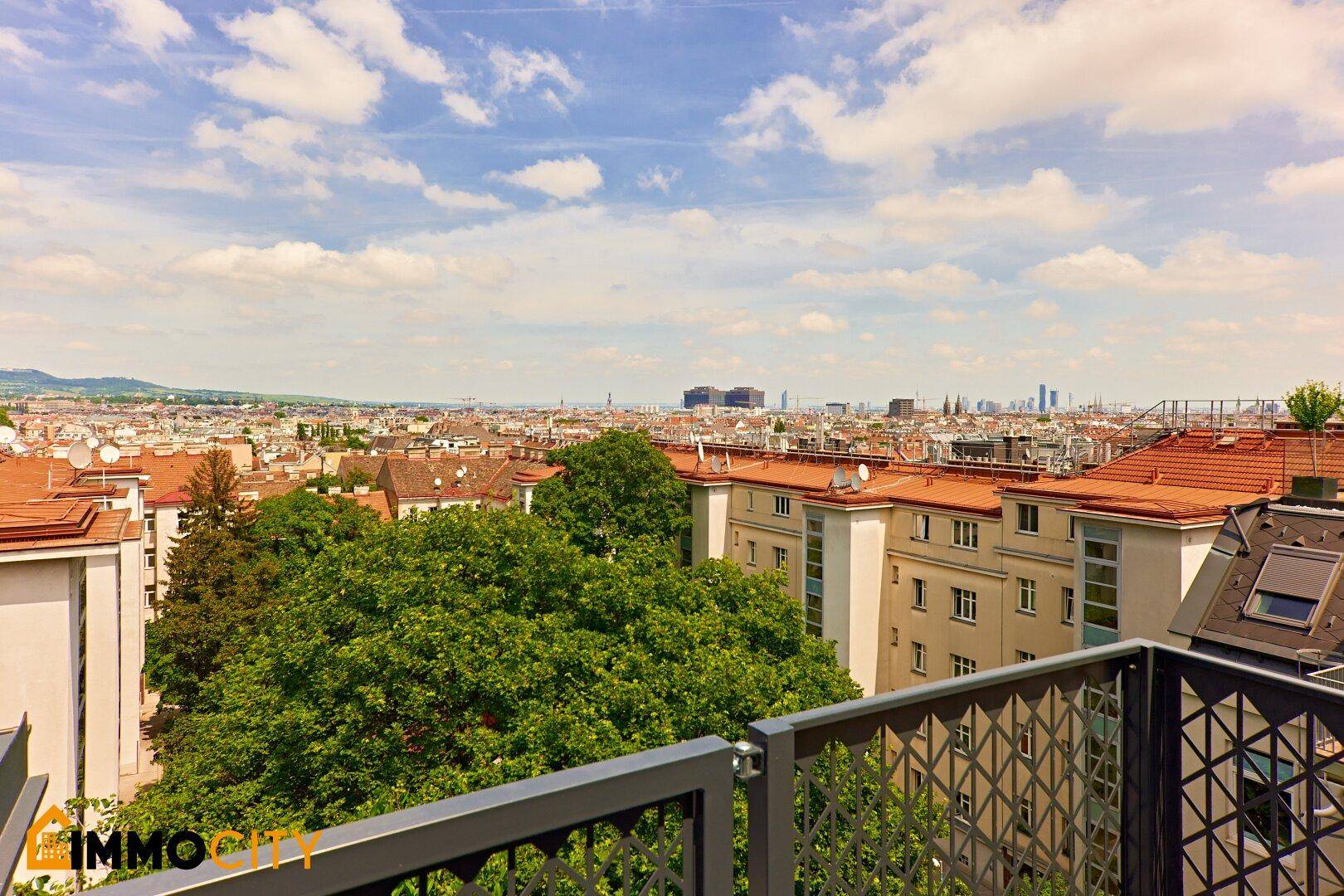 Panoramablick über die Stadt mit vielen Dächern und grünen Bäumen.