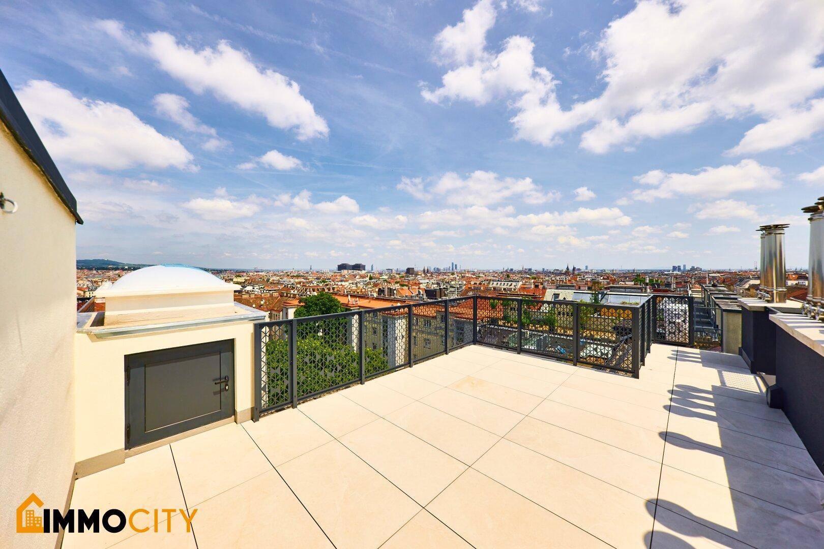 Weitläufige Dachterrasse mit Stadtblick und einem kleinen Gebäude.