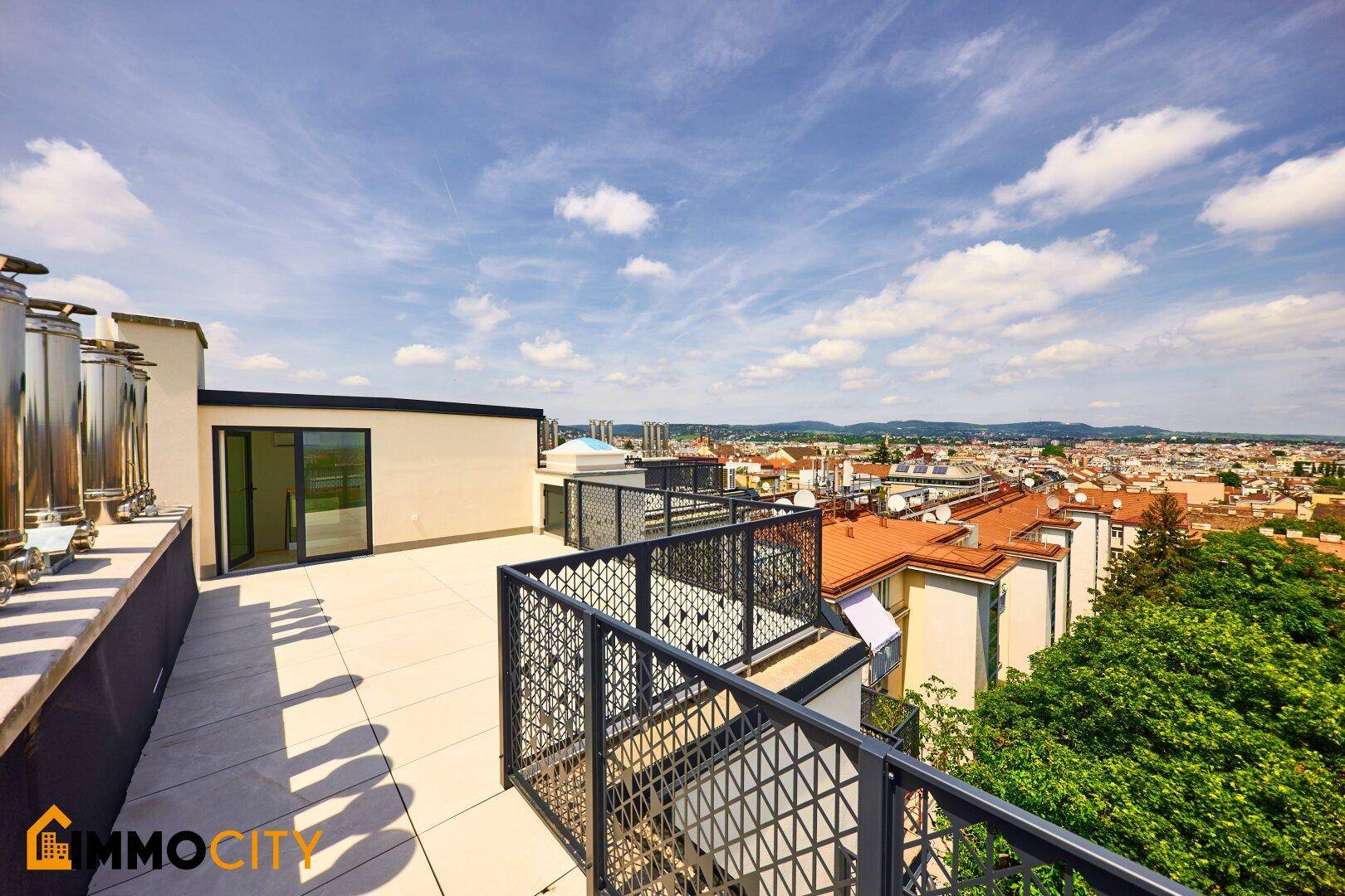 Weitläufige Dachterrasse mit Panoramablick über die Stadt und umliegende Gebäude bei Sonnenschein.