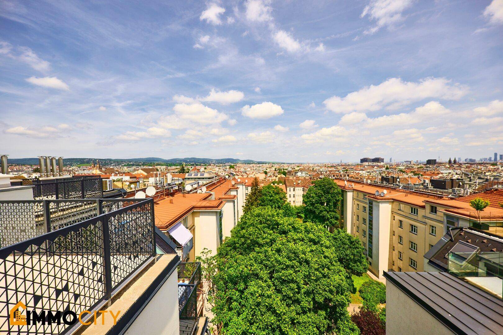 Panoramablick über die Stadt mit vielen Dächern und grünen Bäumen.