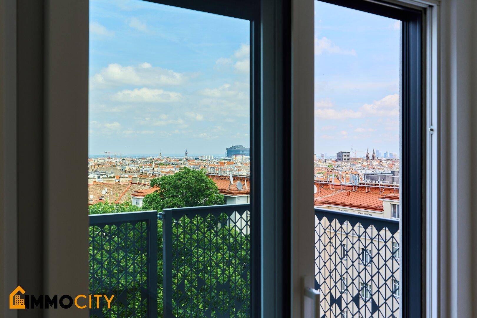 Blick aus dem Fenster auf die Stadt mit ihren Dächern und dem weiten Horizont.